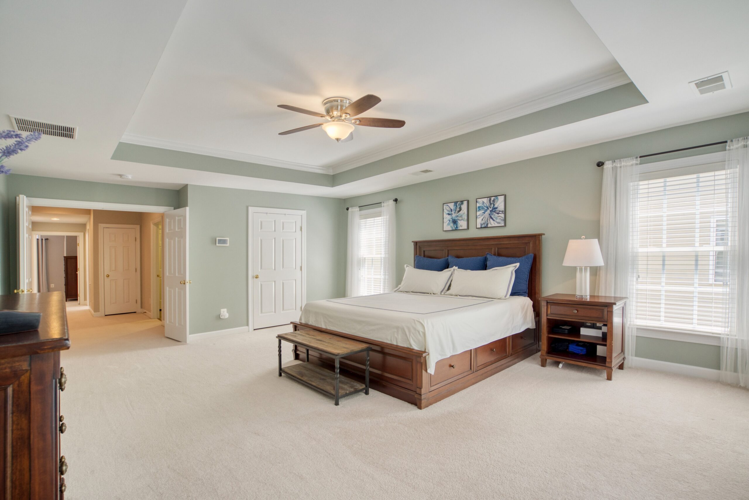 Large master bedroom with tray ceiling and lots of light from large windows