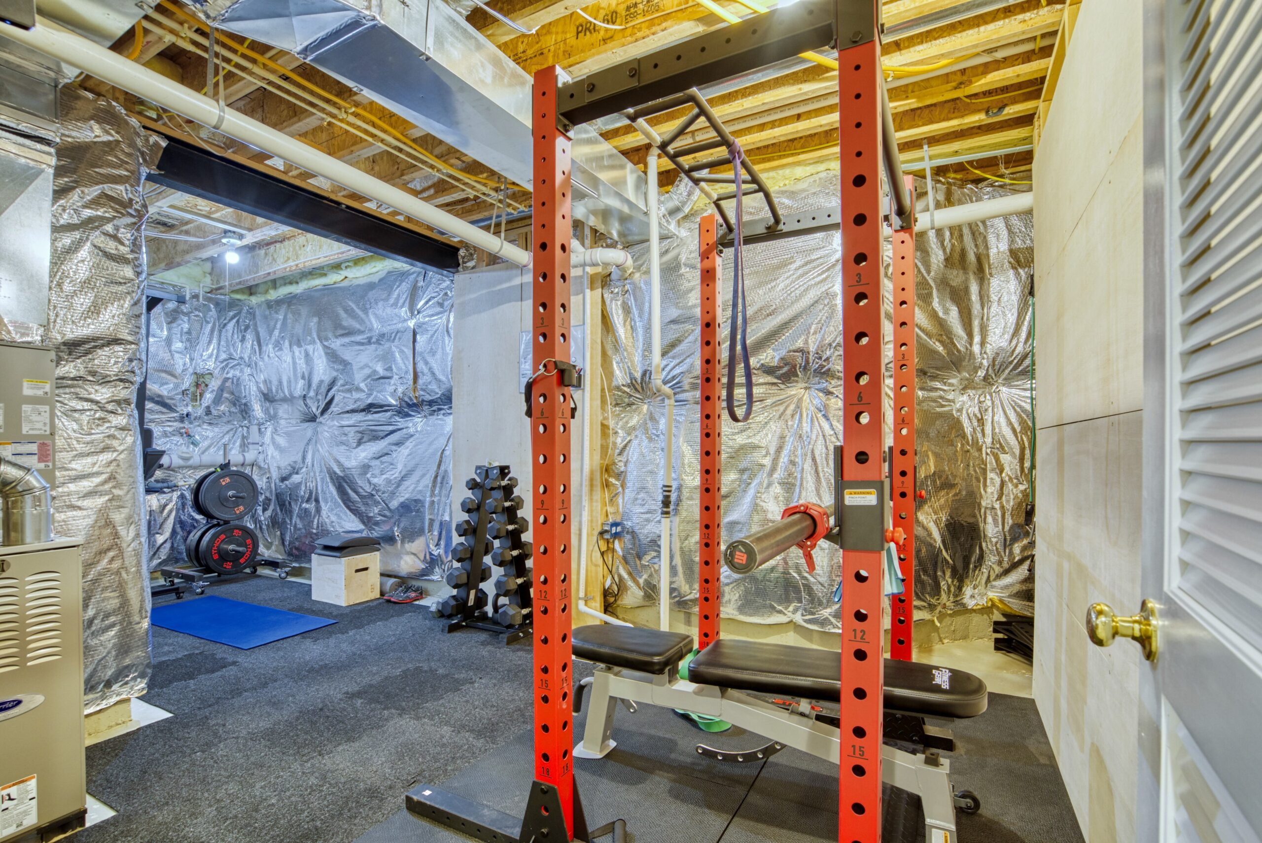Basement unfinished area in a 3-story townhome with exercise equipment including a large squat rack