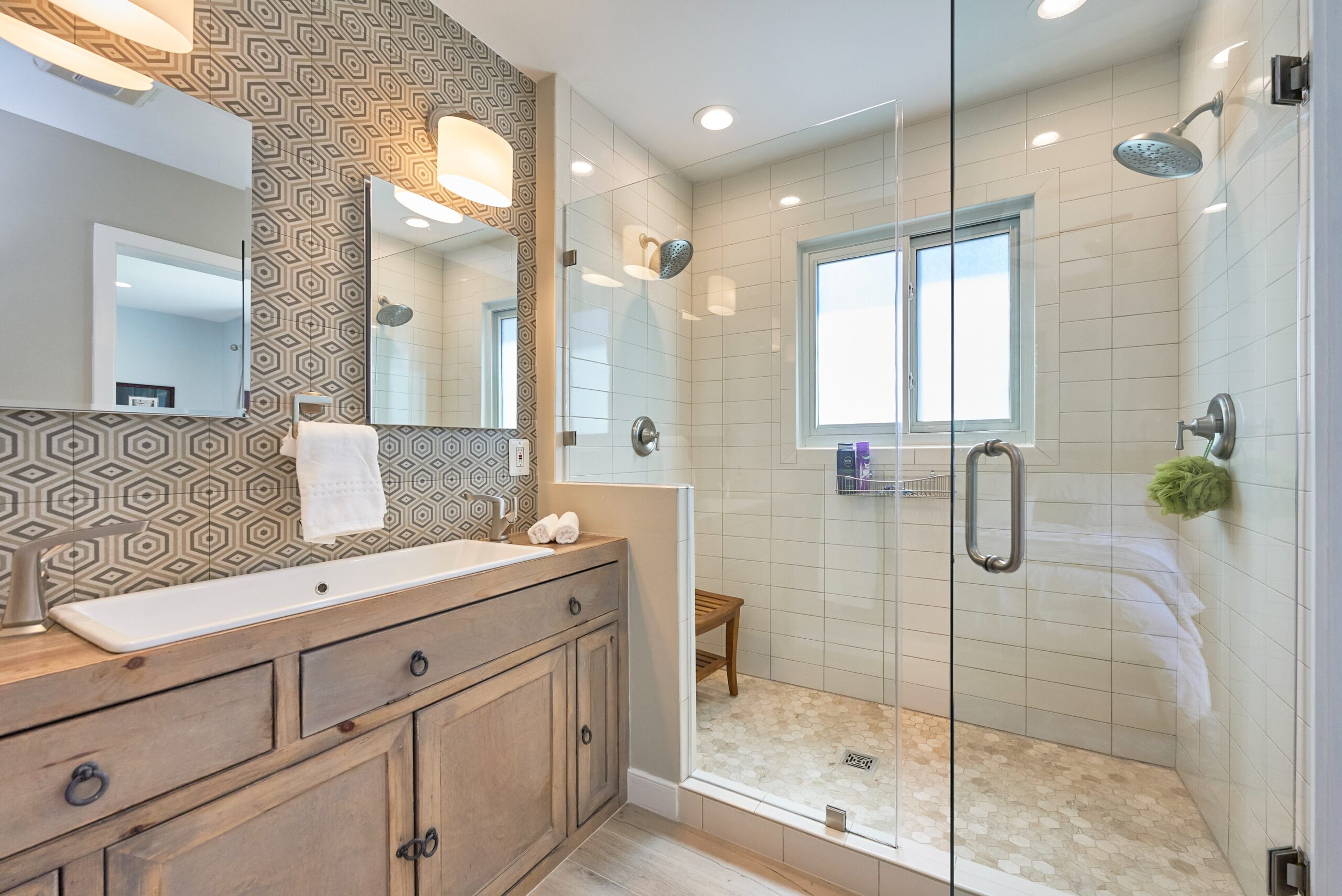 Professional photo of interior of custom home in Falls Church, Virginia. Shows remodeled bathroom with detailed tilework of various designs, large wide sink with 2 faucets in lieu of separate dual-sink vanity.