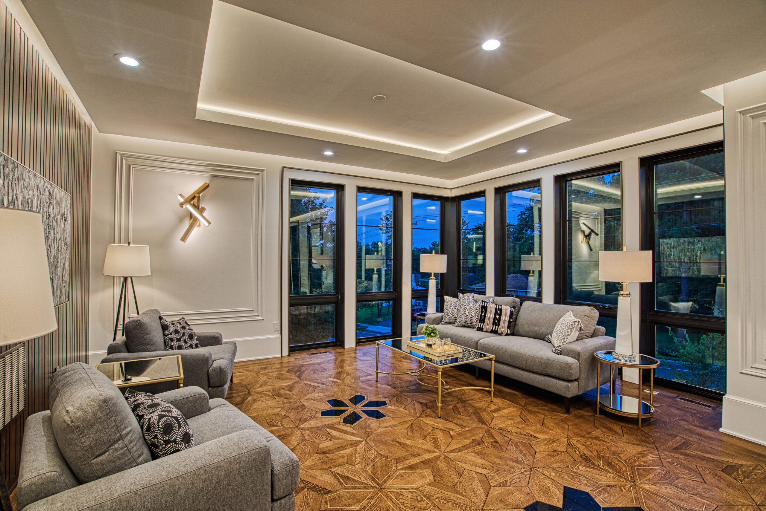 sitting area in luxury new construction home with floor to ceiling windows on two sides, tray ceiling, custom hardwood floors and modern furniture