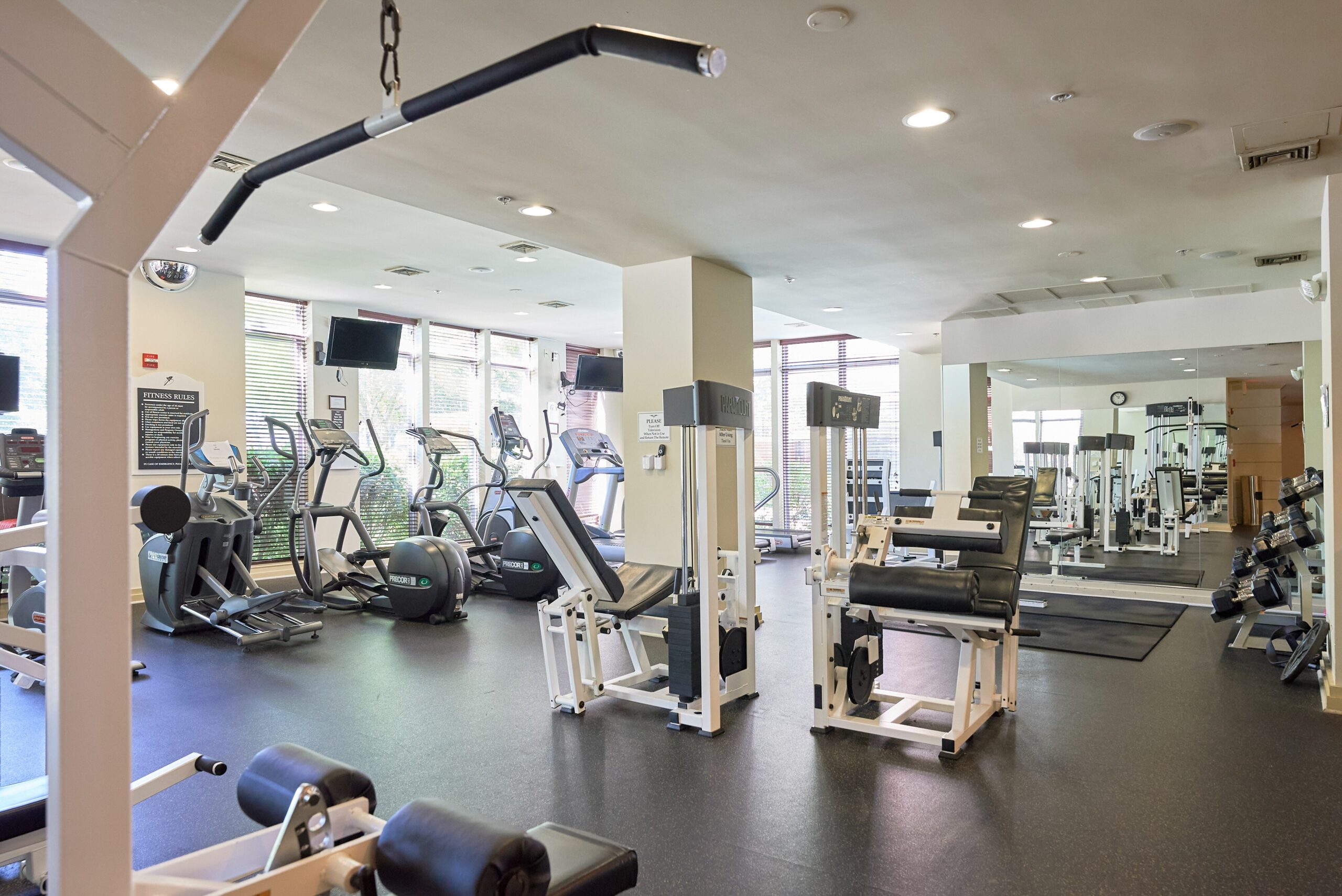 Medium sized fitness center with mirrors and large variety of gym equipment