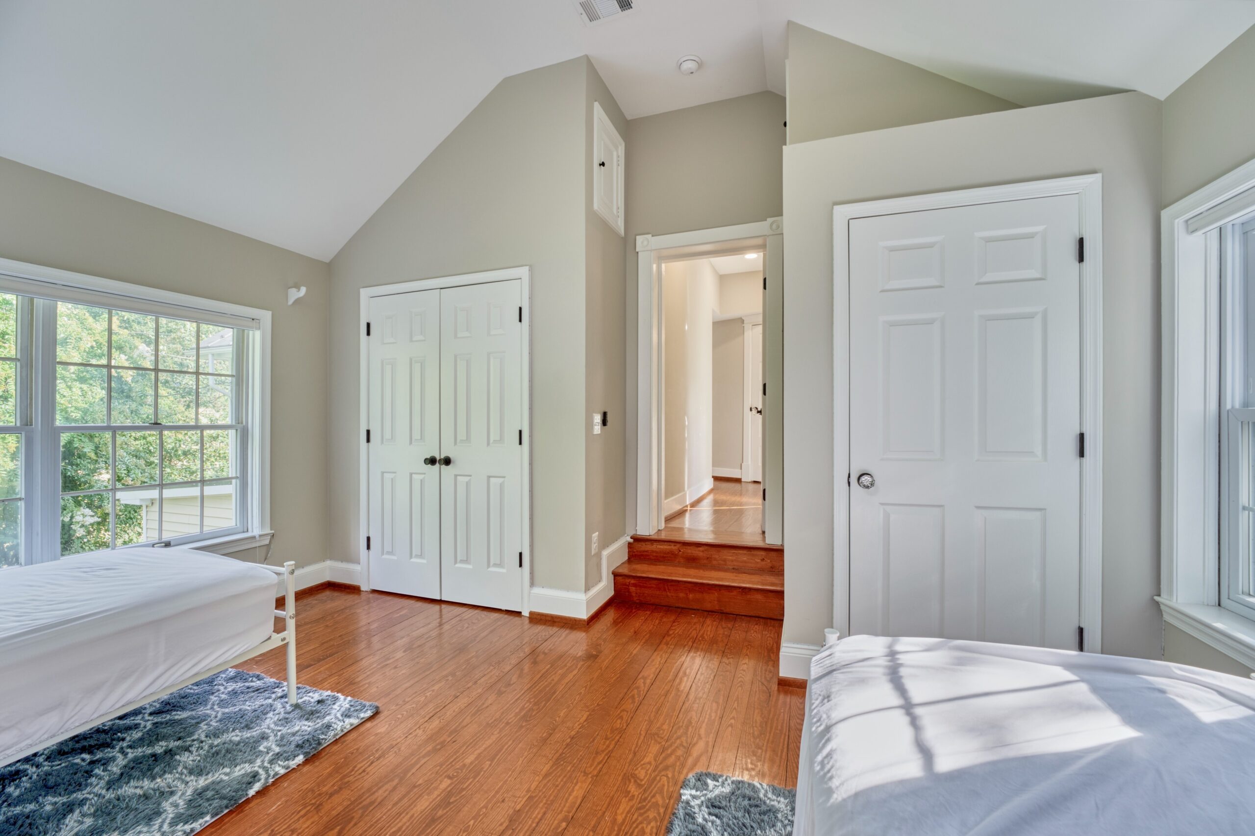 additional perspective of large bedroom with vaulted ceiling in historic home with gleaming hardwood floors.