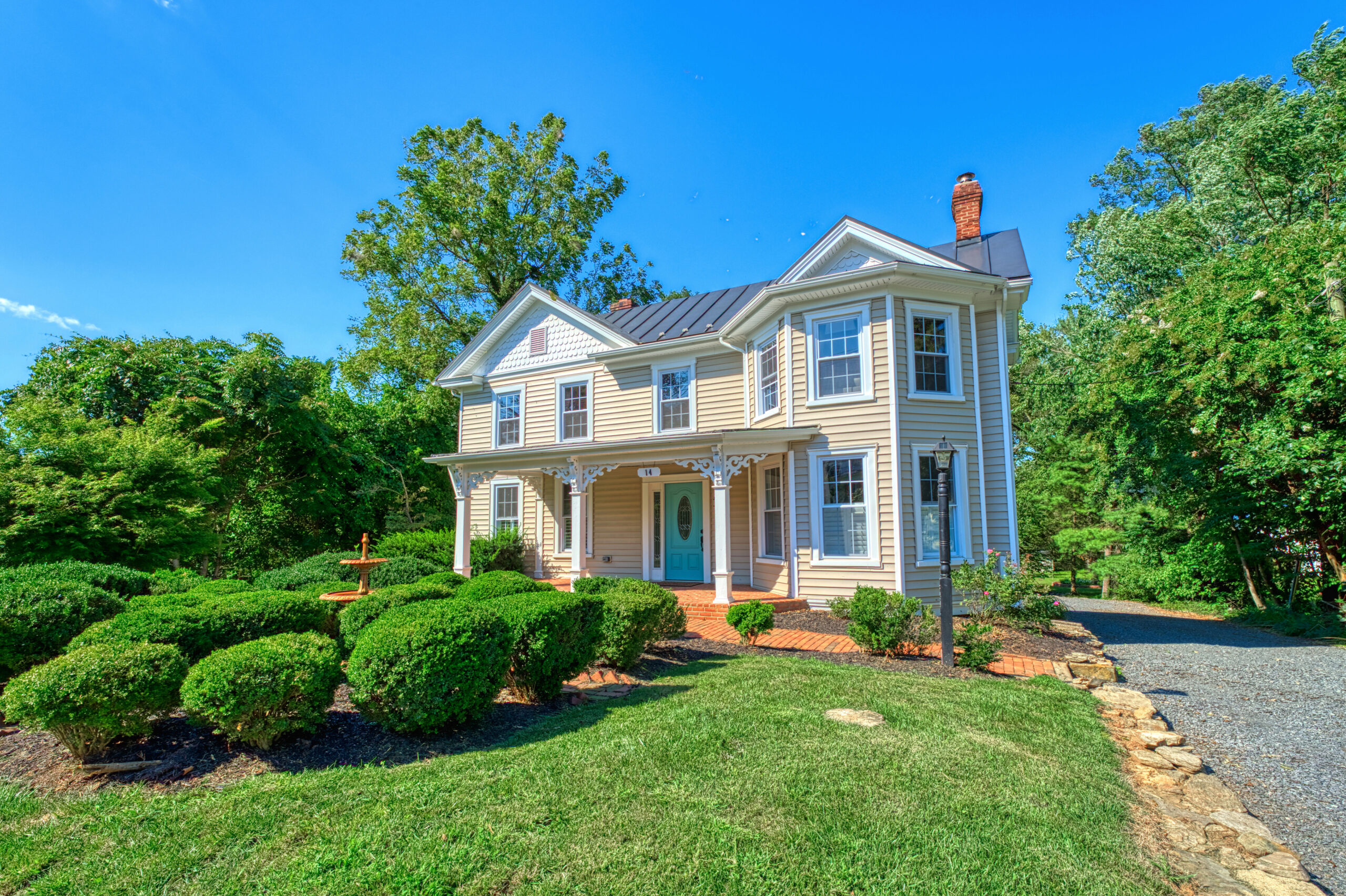 front angled view of historic home in Hamilton, Virginia with beige siding and landscaped shrubs