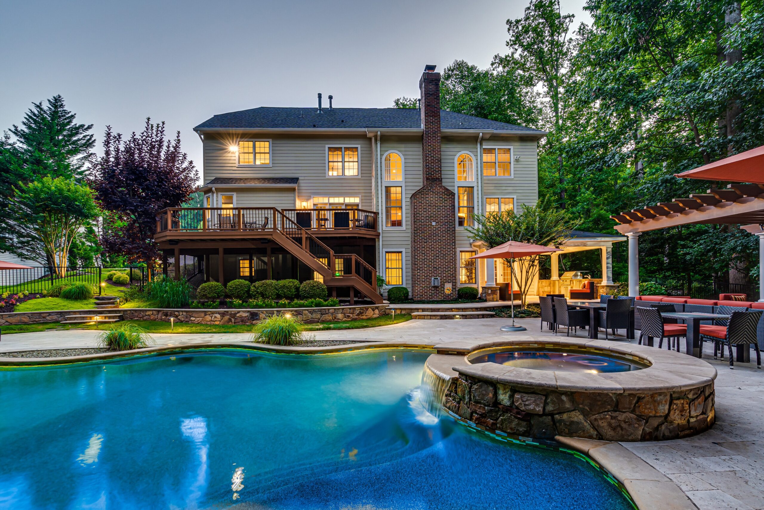 Exterior at dusk showing pool and hot tub in the foreground and lounge area and home in the background. 10703 Ox Croft Ct, Fairfax Station, VA