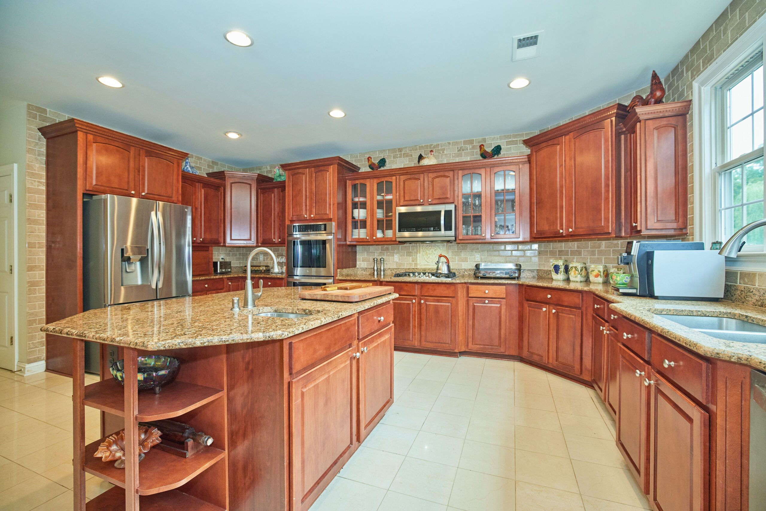 Flash photo of a large kitchen with walnut cabinets, brown granite counters and stainless appliances