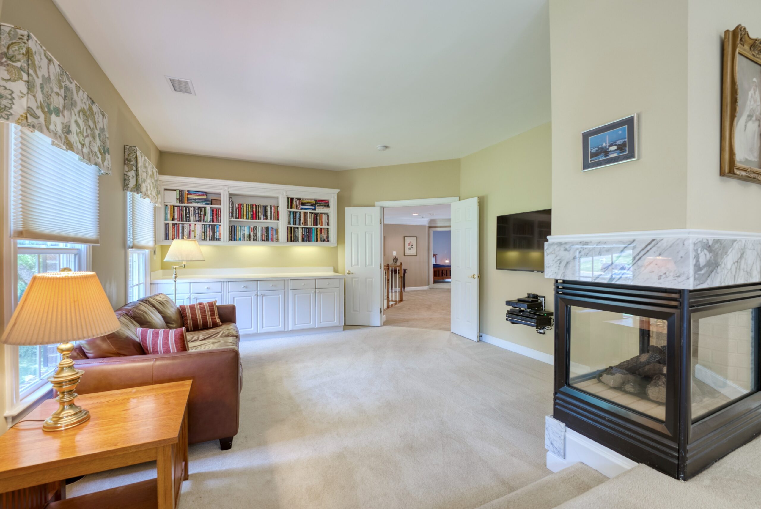 Loft lounge area with built-in bookshelves and cabinets and a gas fireplace. 10703 Ox Croft Ct, Fairfax Station, VA