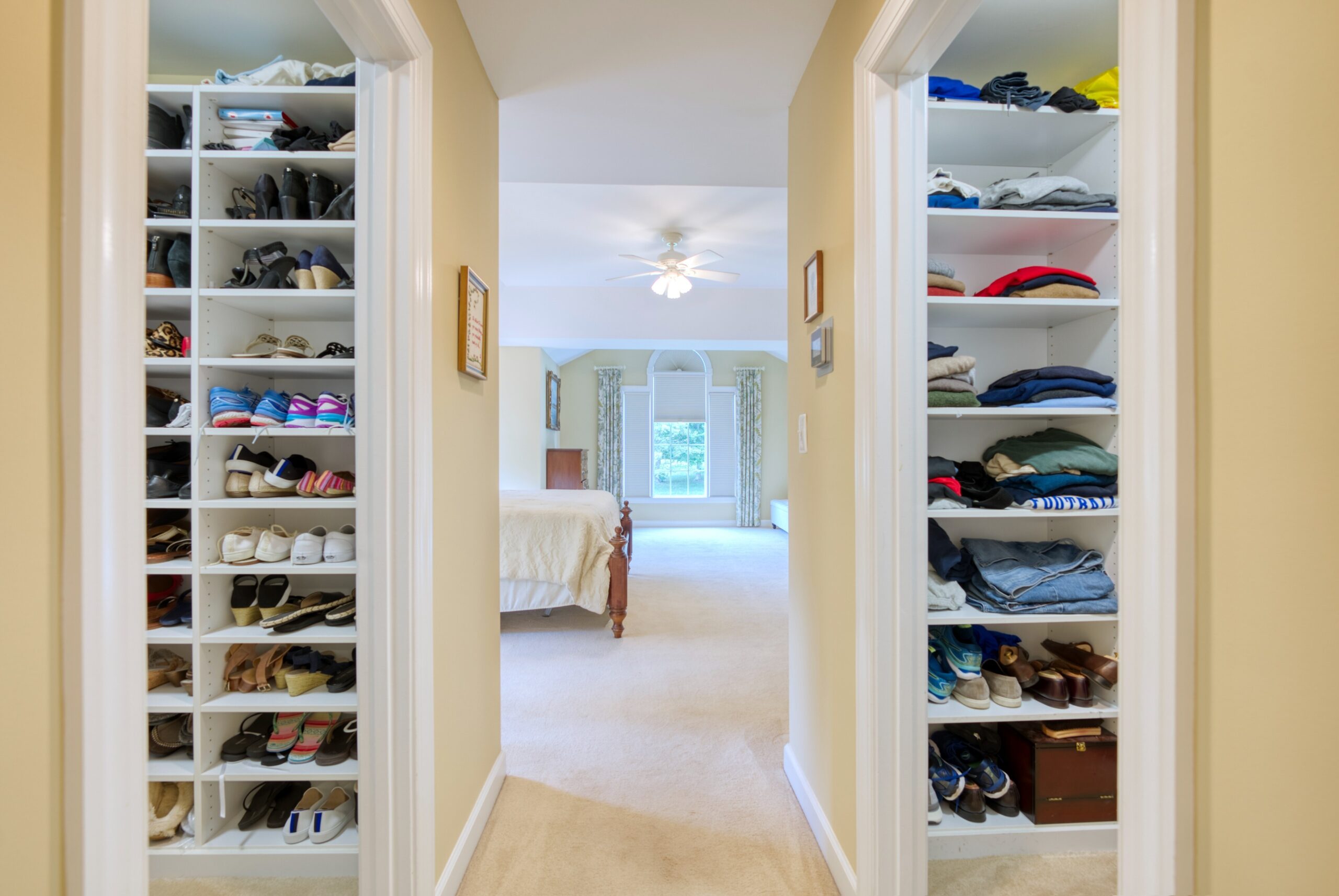 hallway in Master bedroom suite, with his and her closets showing shoe shelves on either side and bedroom in the background. 10703 Ox Croft Ct, Fairfax Station, VA