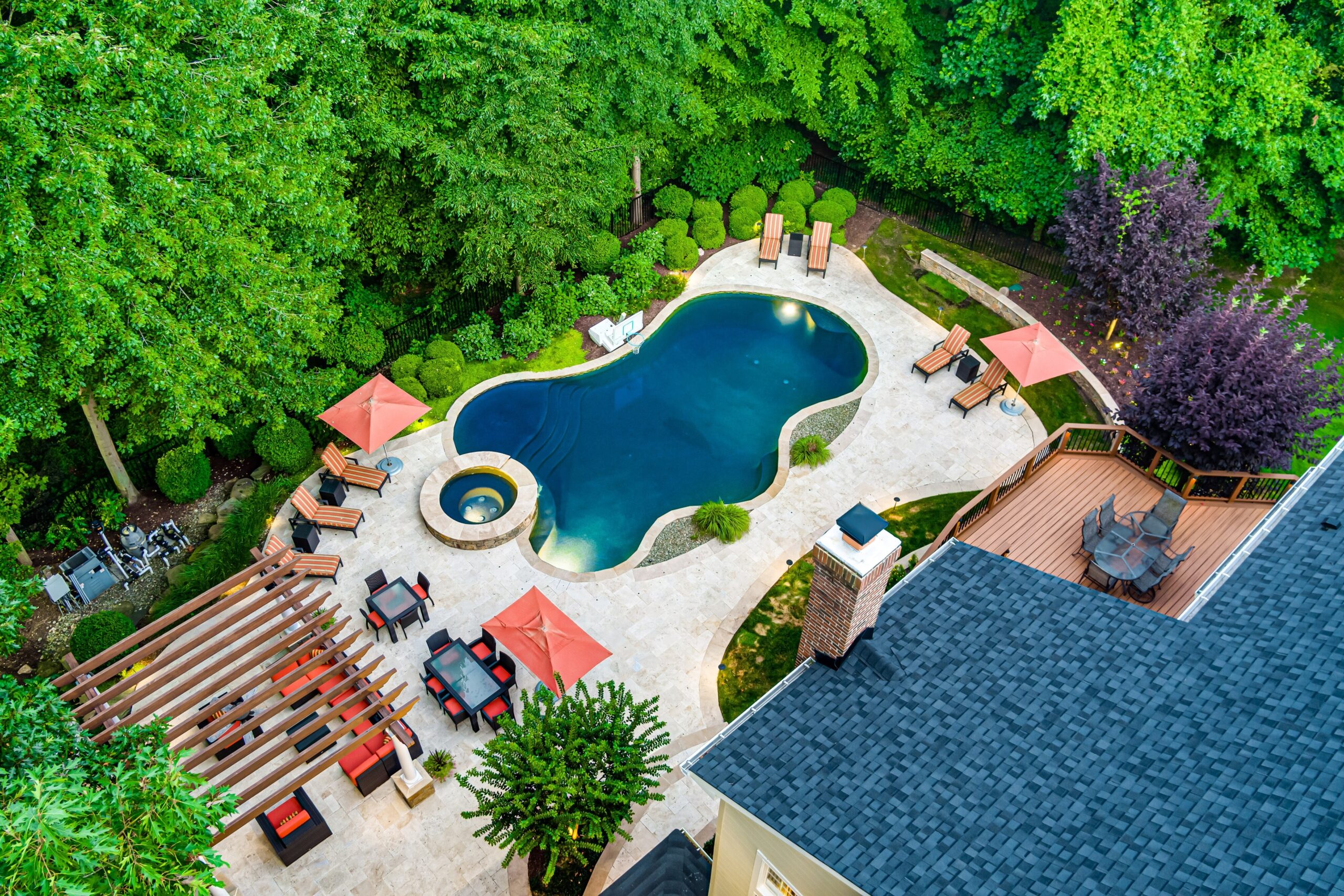 Aerial drone photo of the backyard space, showing the pool, hot tub, lounge and seating areas, as well as the upper deck. 10703 Ox Croft Ct, Fairfax Station, VA