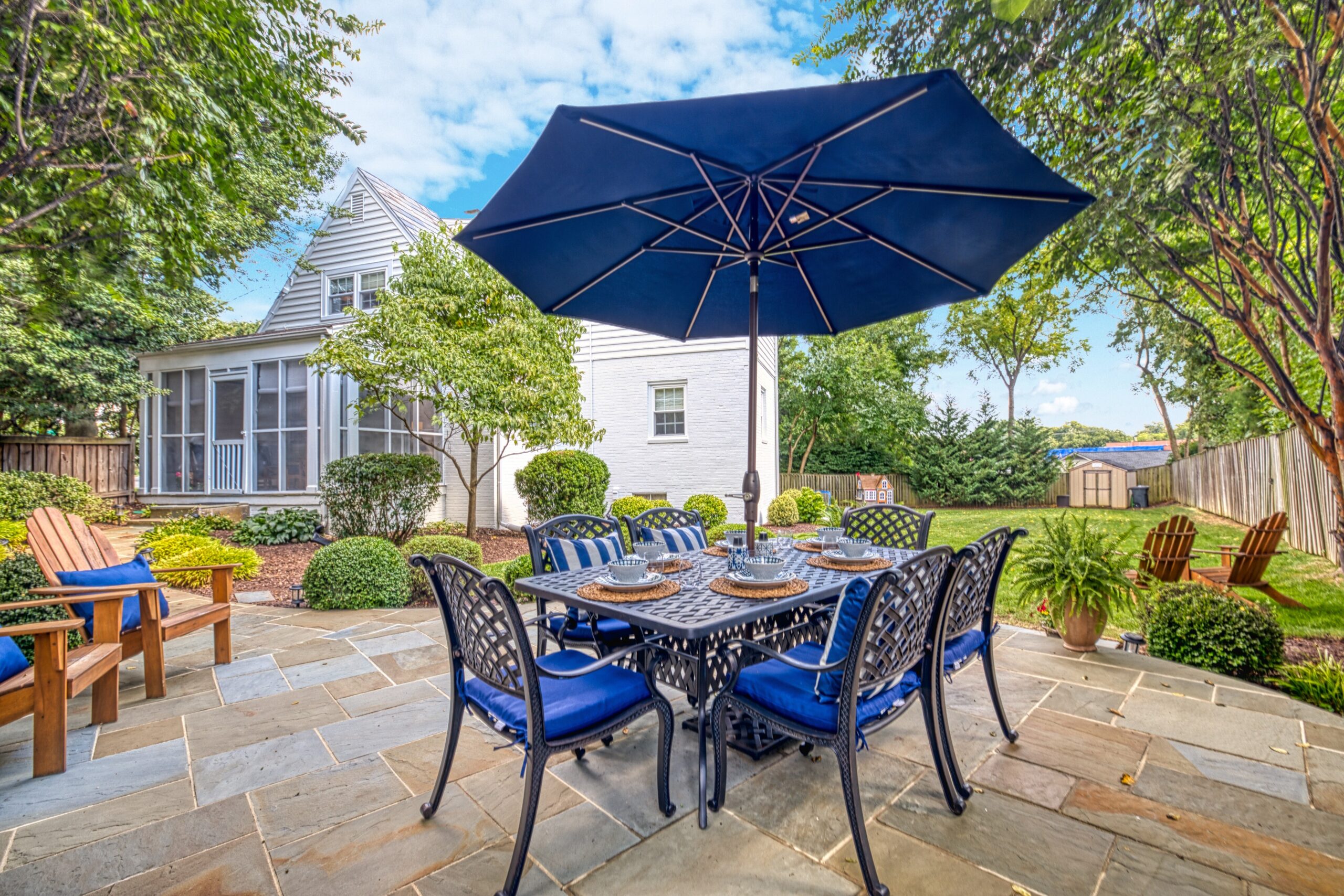Exterior professional photo of stone patio behind 1946 Cape Cod home in Alexandria, VA with navy patio furniture