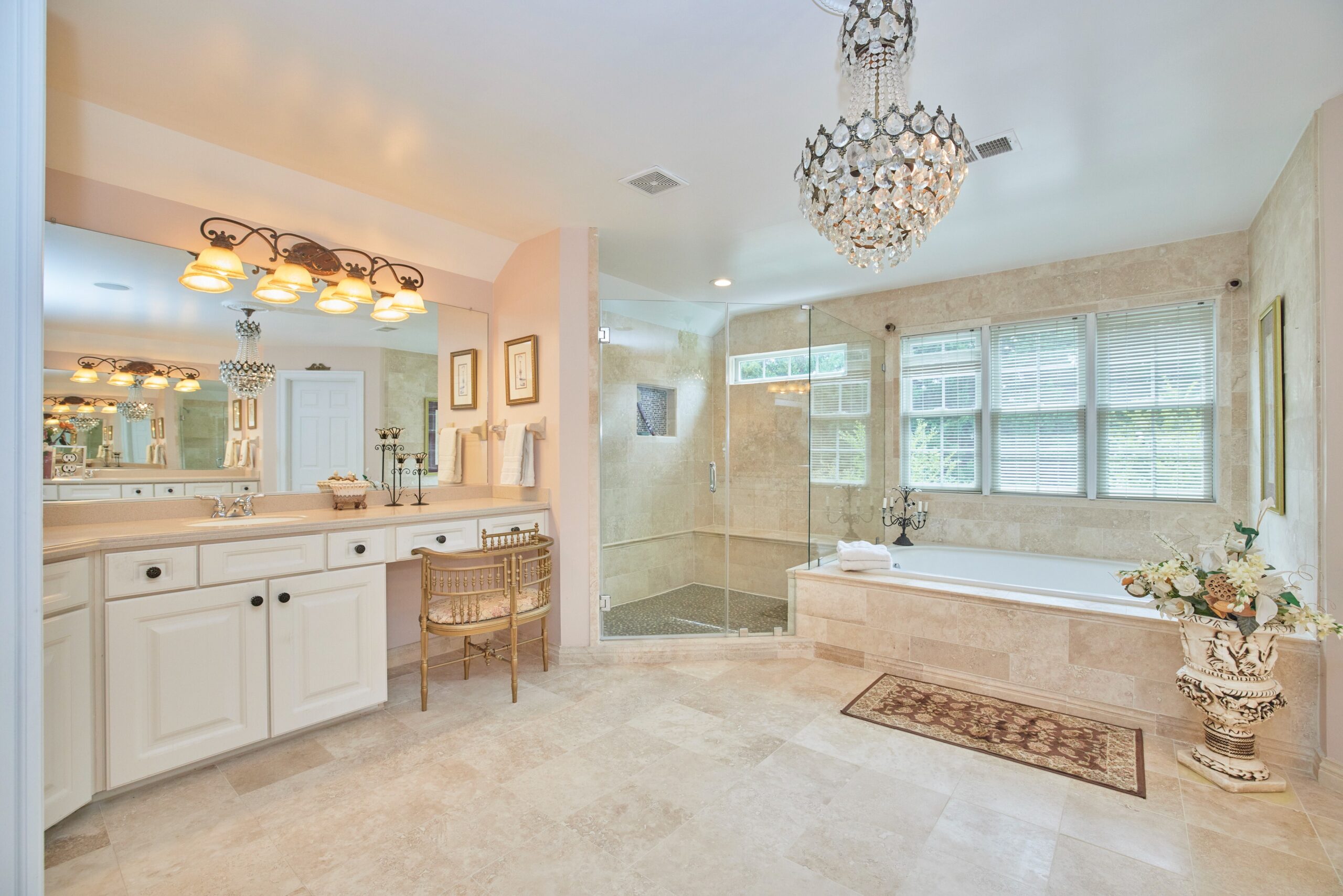 Flash photo of the master bathroom in a large master bedroom suite, with crystal chandelier, soaking tub, large shower and large vanity