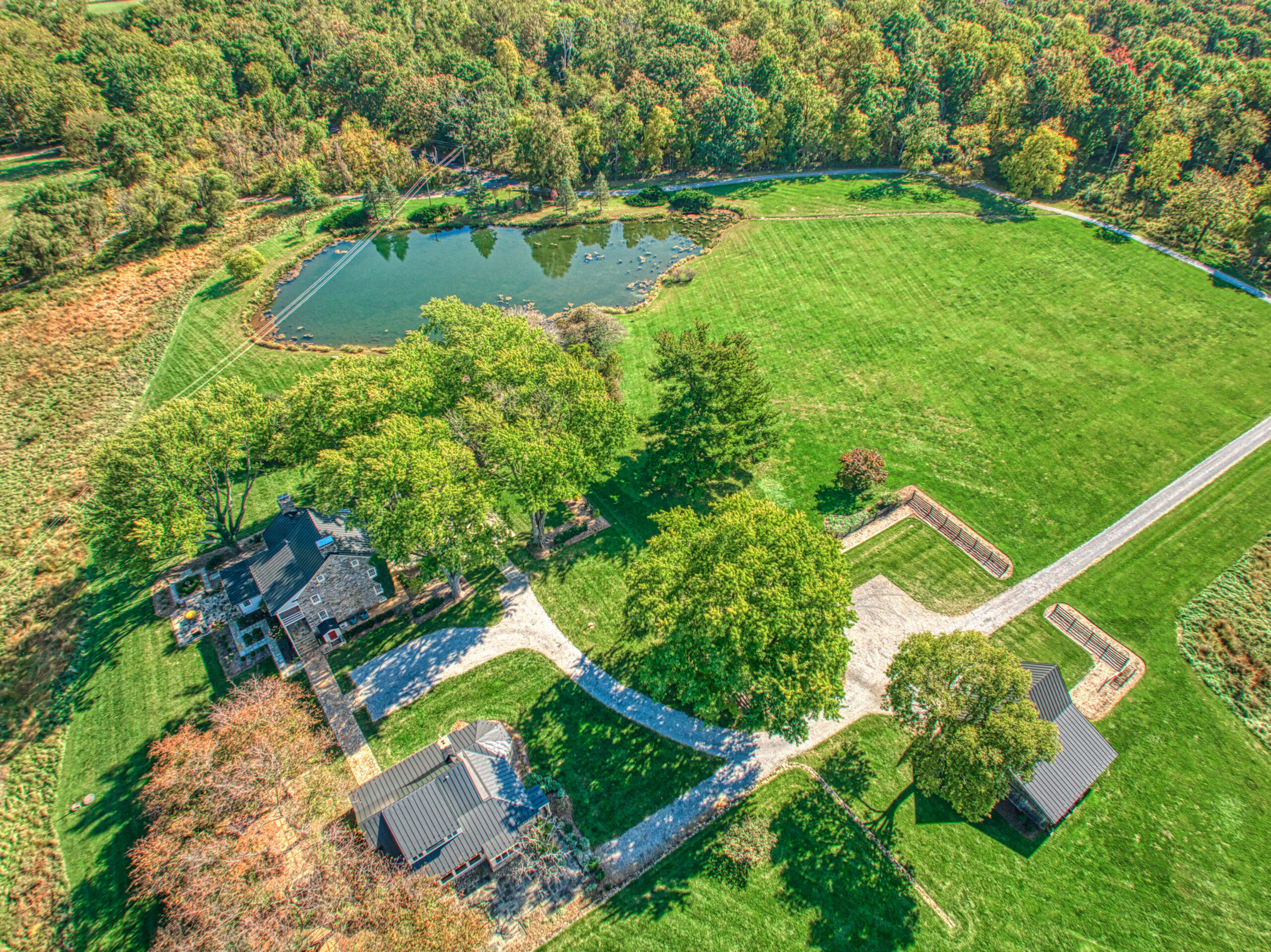 Professional aerial drone photo of Historic Hearthstone Manor: 35428 Appalachian Trail Rd, Round Hill, Virginia - showing 3 individual structures (2 homes and one detached garage), long driveway and large pond