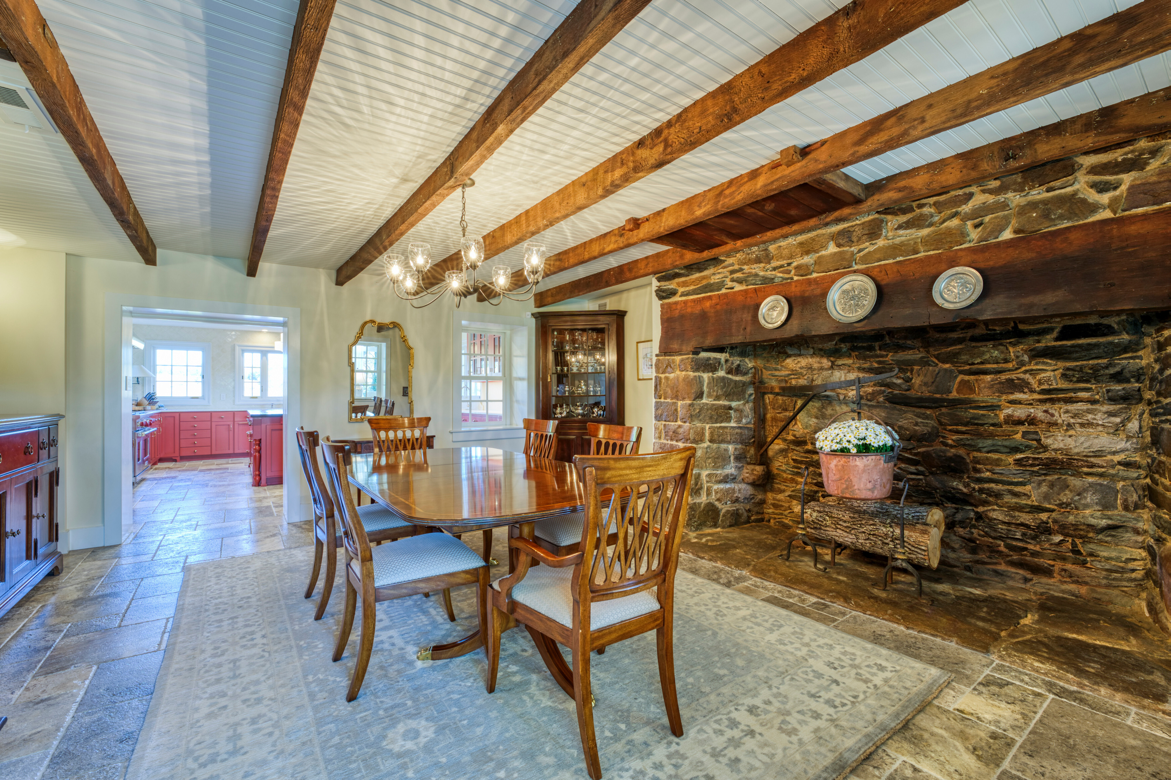 Professional interior photo of main house of Historic Hearthstone Manor: 35428 Appalachian Trail Rd, Round Hill, Virginia - showing formal dining room with wooden dining set, exposed wooden ceiling beams and huge stone fireplace