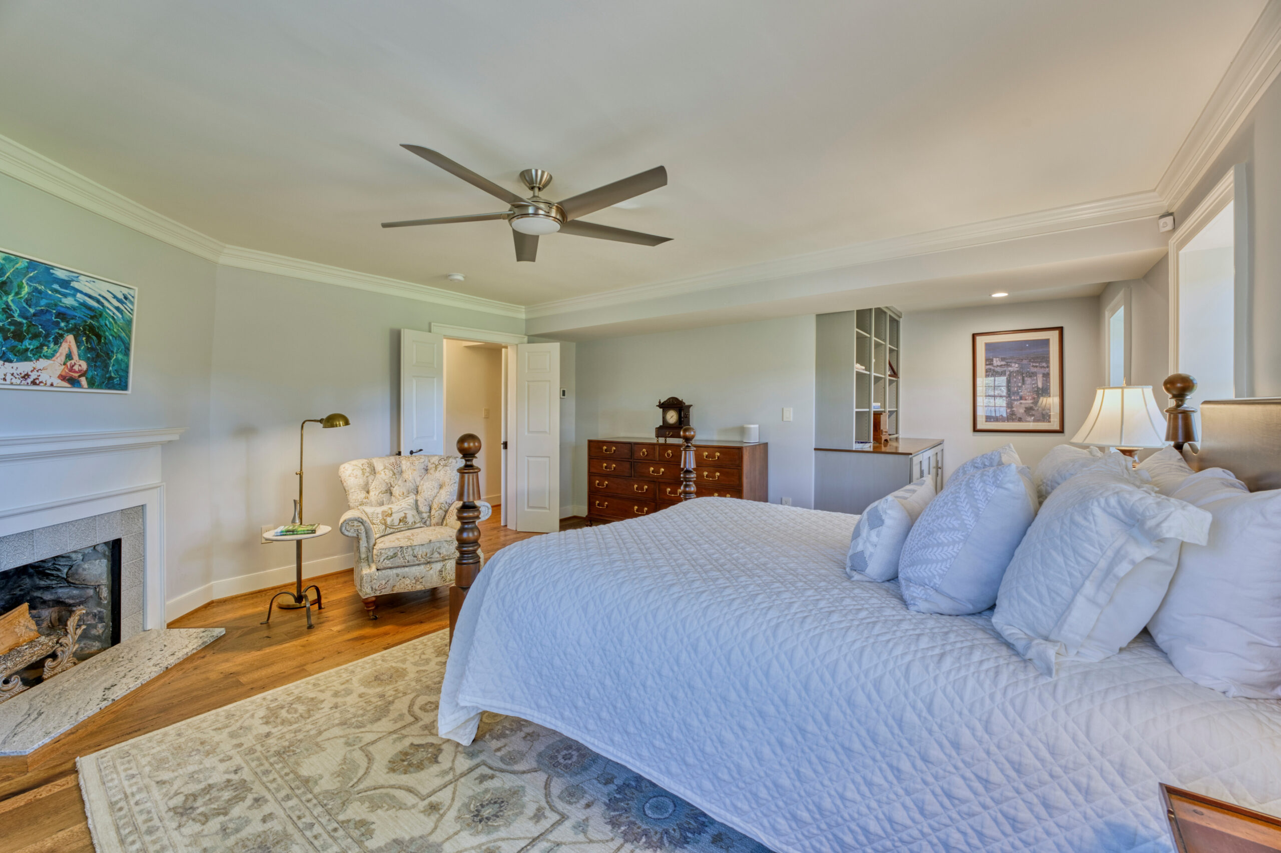 Professional interior photo of main house of Historic Hearthstone Manor: 35428 Appalachian Trail Rd, Round Hill, Virginia - showing master bedroom with fireplace, ceiling fan, and reading nook with built-in shelves in the background
