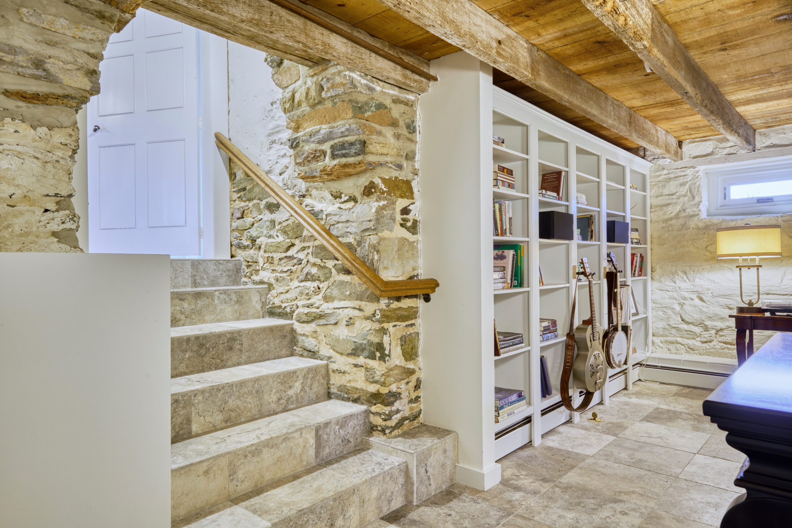 Professional interior photo of main house of Historic Hearthstone Manor: 35428 Appalachian Trail Rd, Round Hill, Virginia - showing short stone staircase to finished basement sitting room with built-in bookshelves