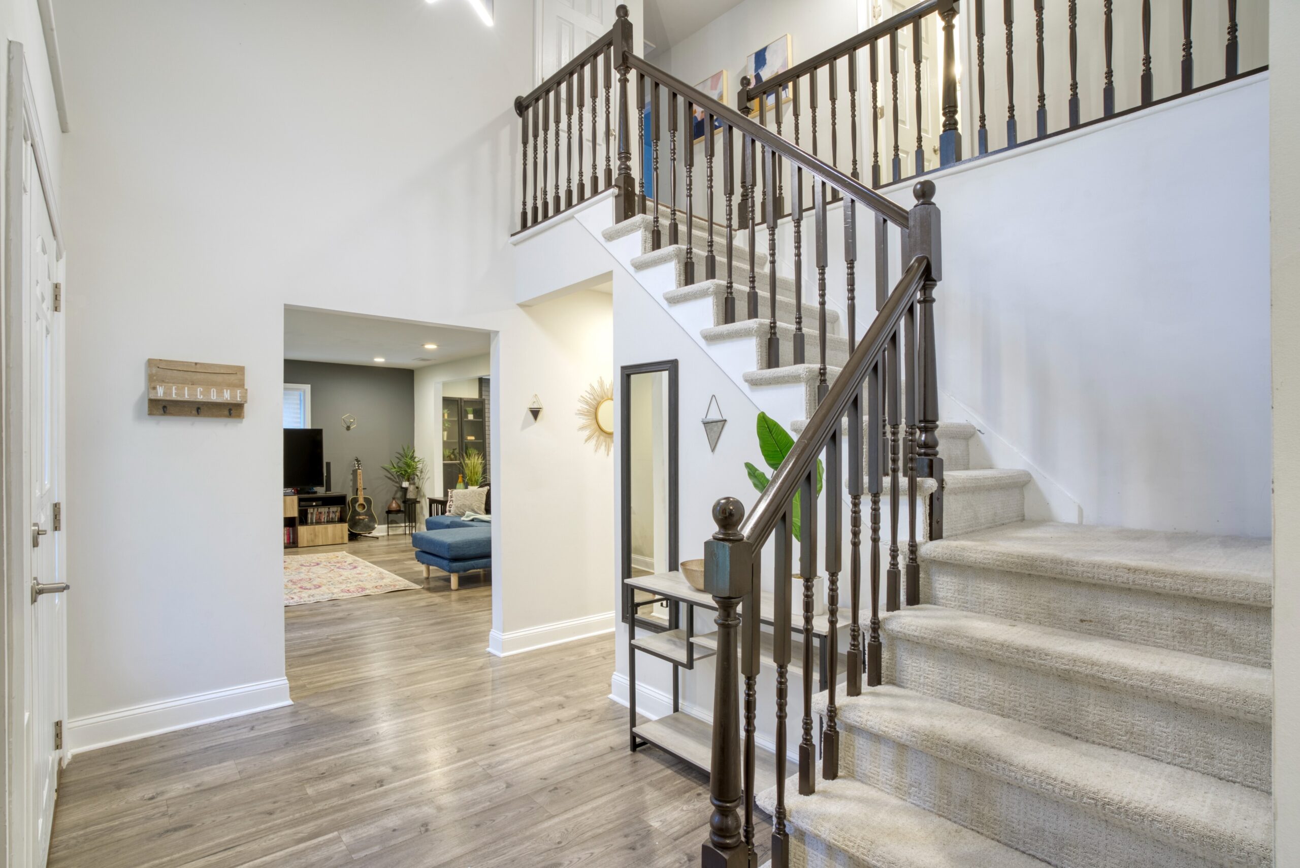 Interior professional photo of 9015 Longbow Rd - showing the entryway with carpeted staircase to second floor, glimpse of living room through the open doorway