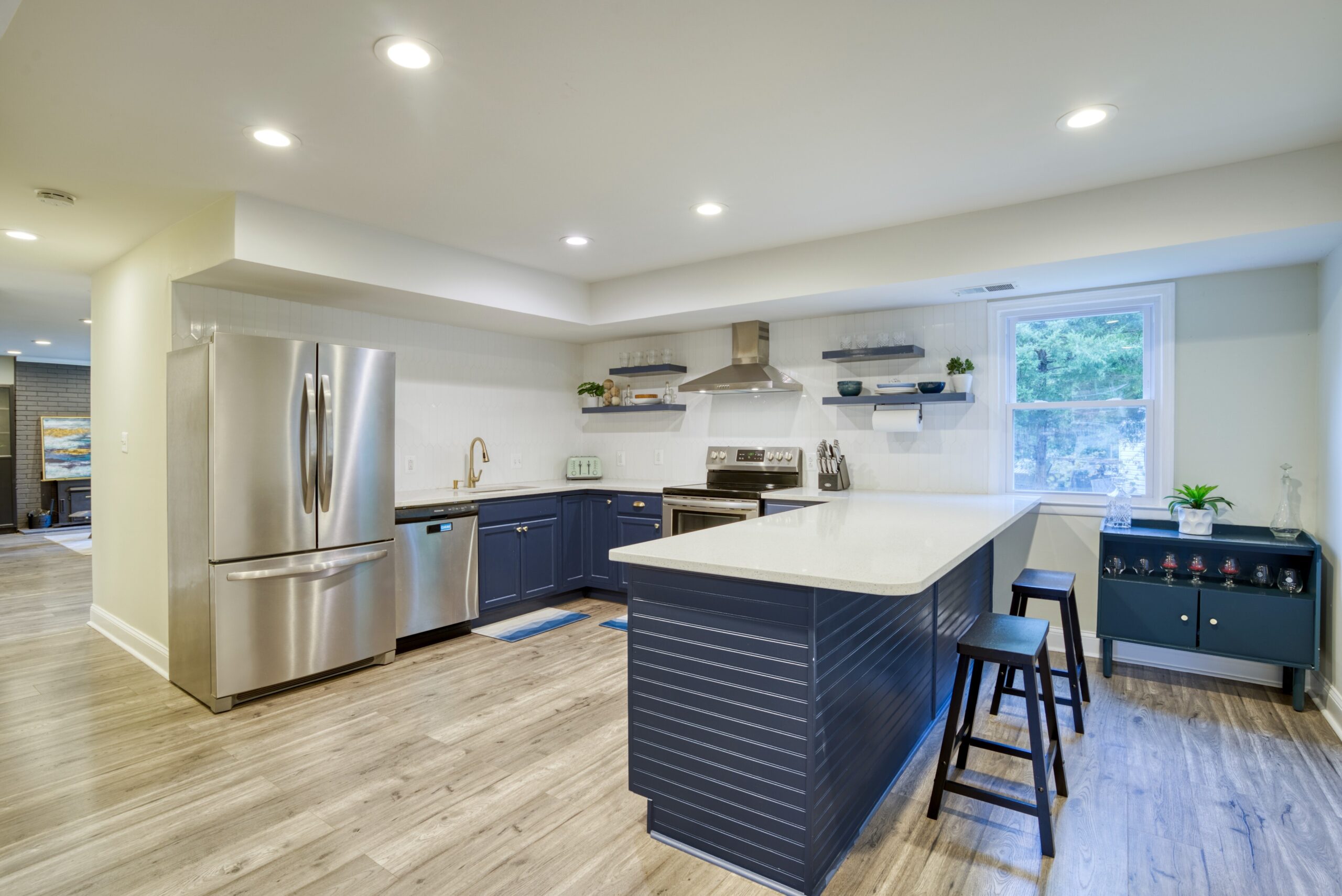 Interior professional photo of 9015 Longbow Rd - showing newly remodeled and upgraded kitchen with stainless appliances, huge quartz peninsula for dining, and navy contrast colors