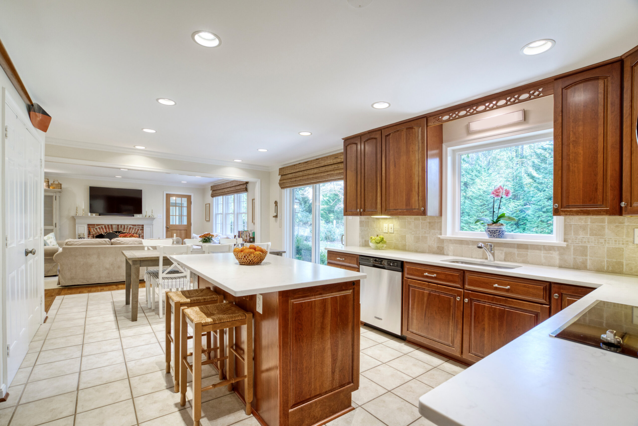 Professional interior photo of 8305 River Falls Dr, Potomac, MD - showing open kitchen with oak cabinets and center island with barstools. Family room visible in the background
