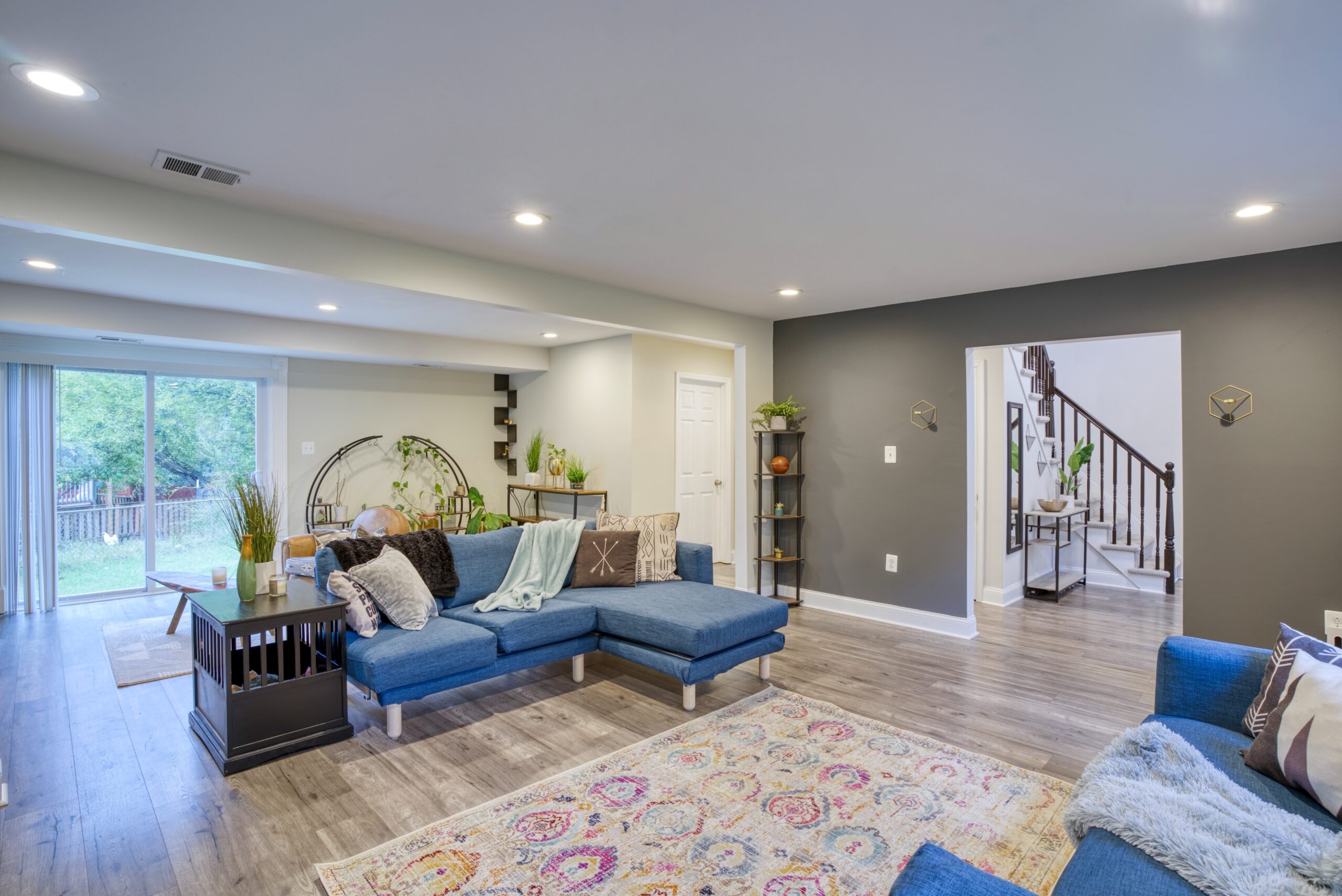 Interior professional photo of 9015 Longbow Rd - showing modern staged living room, hallway and staircase to second floor in the background.