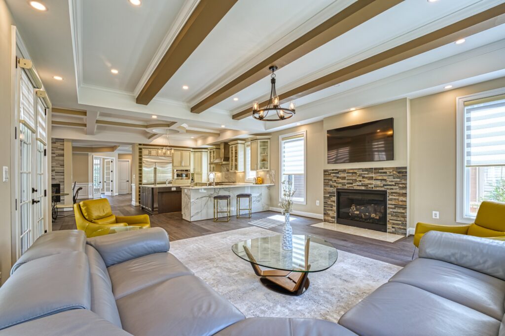 professional Fusion photo of the interior of a home in McLean, VA - showing tray ceiling with exposed beams, open floor plan merging kitchen with living room and gas fireplace.