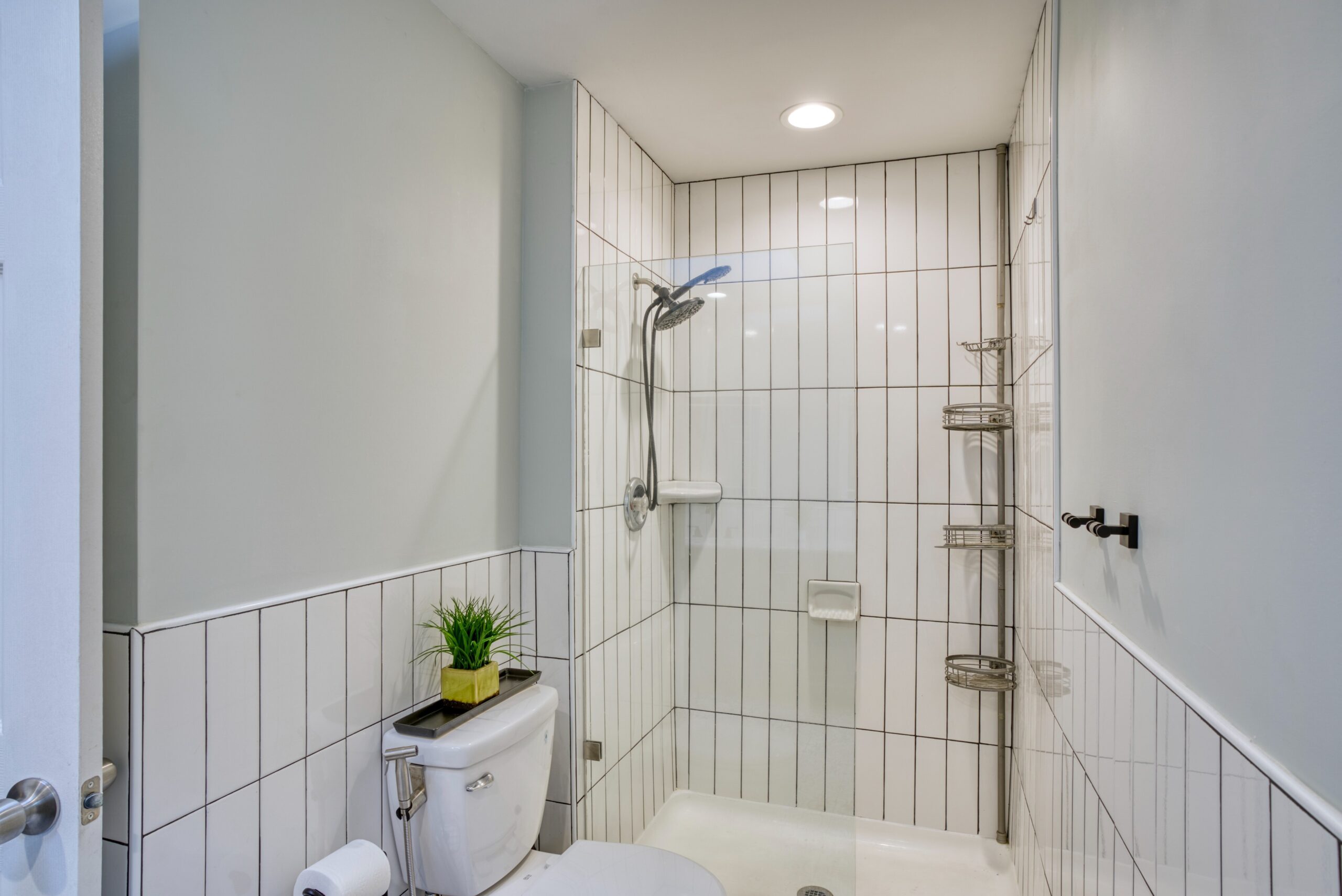 Interior professional photo of 9015 Longbow Rd - showing newly remodeled bathroom with vertical subway tiles in the shower and lower section of bathroom walls.