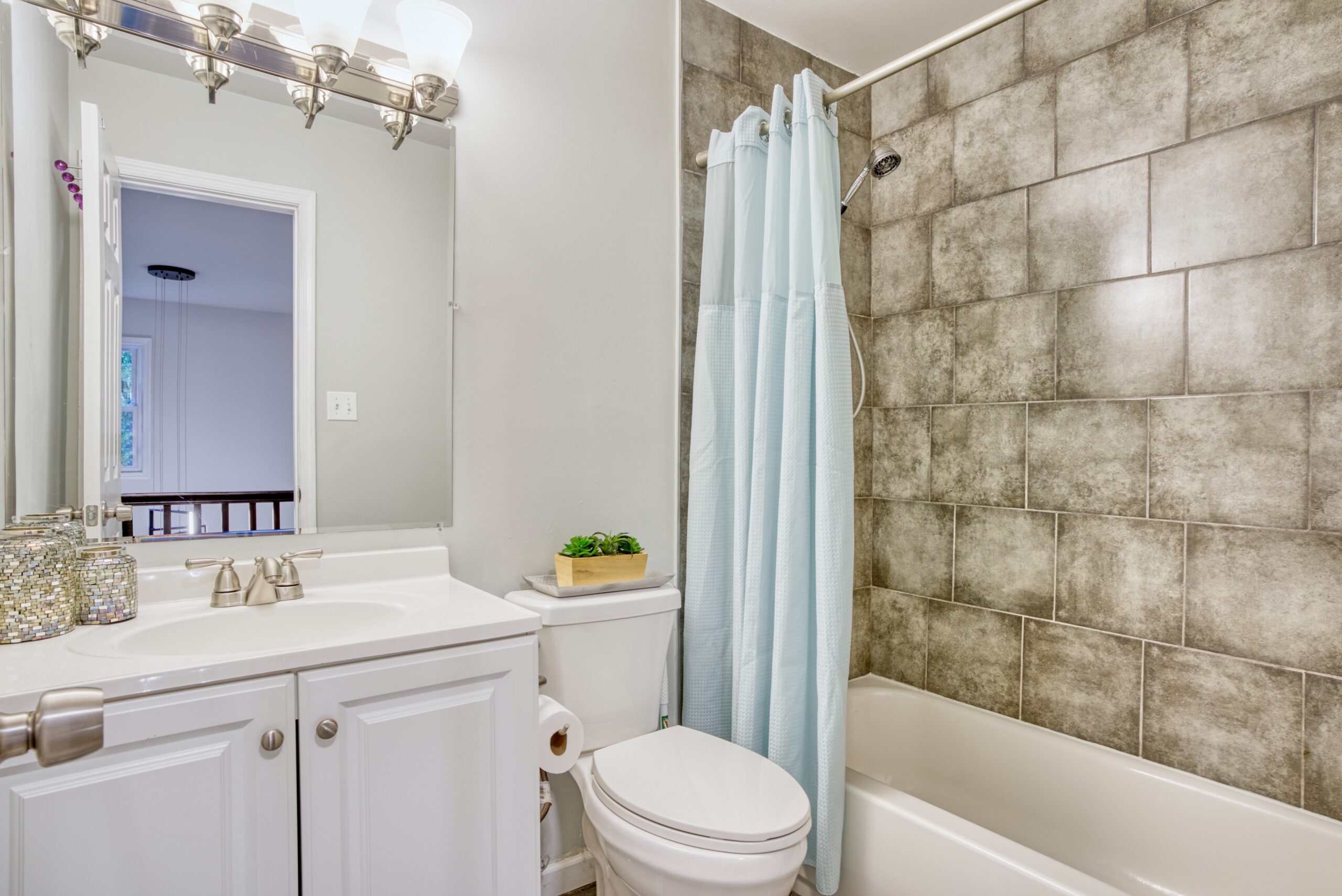 Interior professional photo of 9015 Longbow Rd - showing newly remodeled bathroom with large subway tiles in the shower that look like concrete