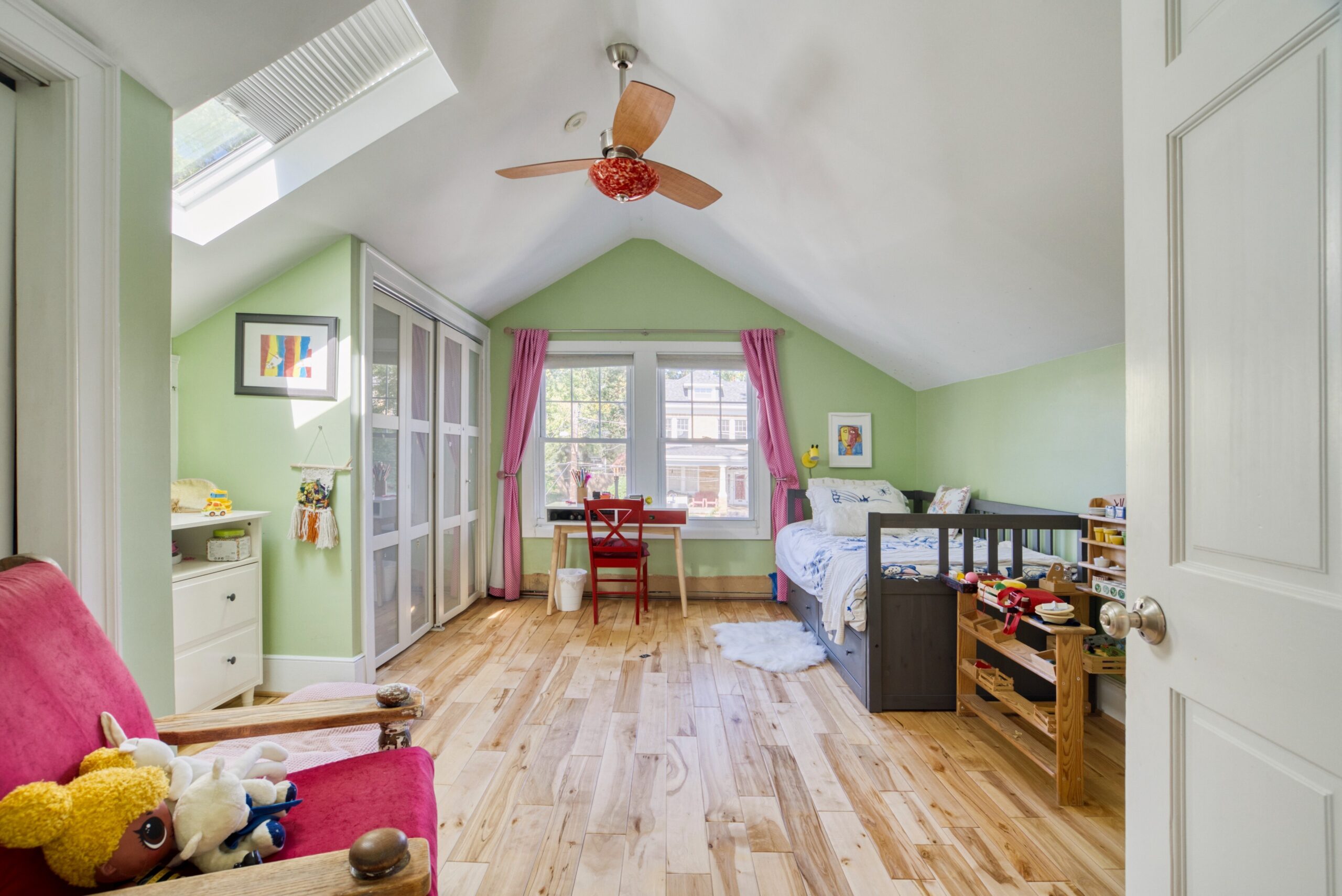 Interior professional photo of 1826 Varnum St NW - showing a bedroom/playroom with vaulted ceiling, skylight, hardwood floors, and a nook with ceiling fan