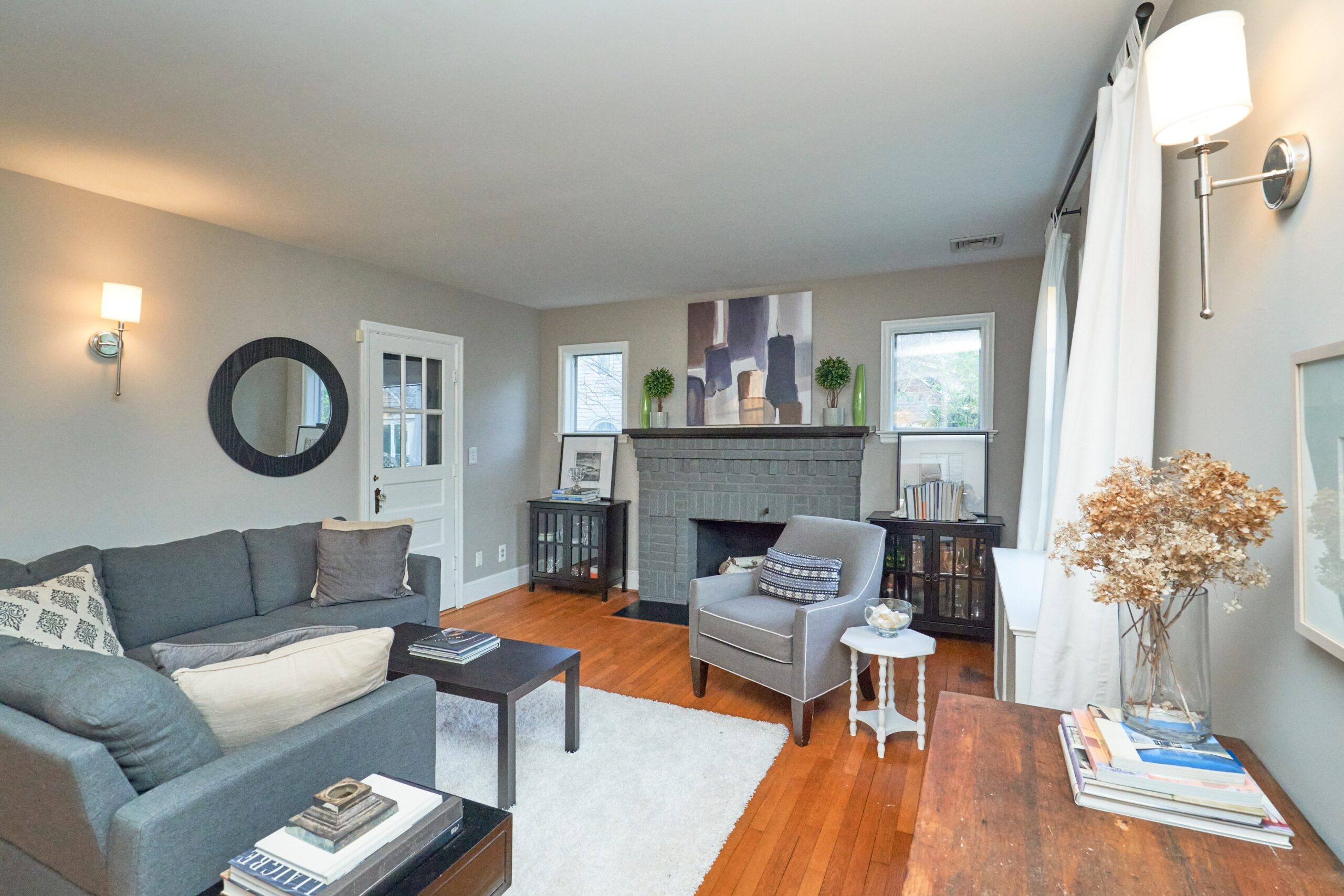 Professional interior photo of 5933 16th St N, Arlington, VA - showing the front living room with grey painted brick fireplace and hardwood floors