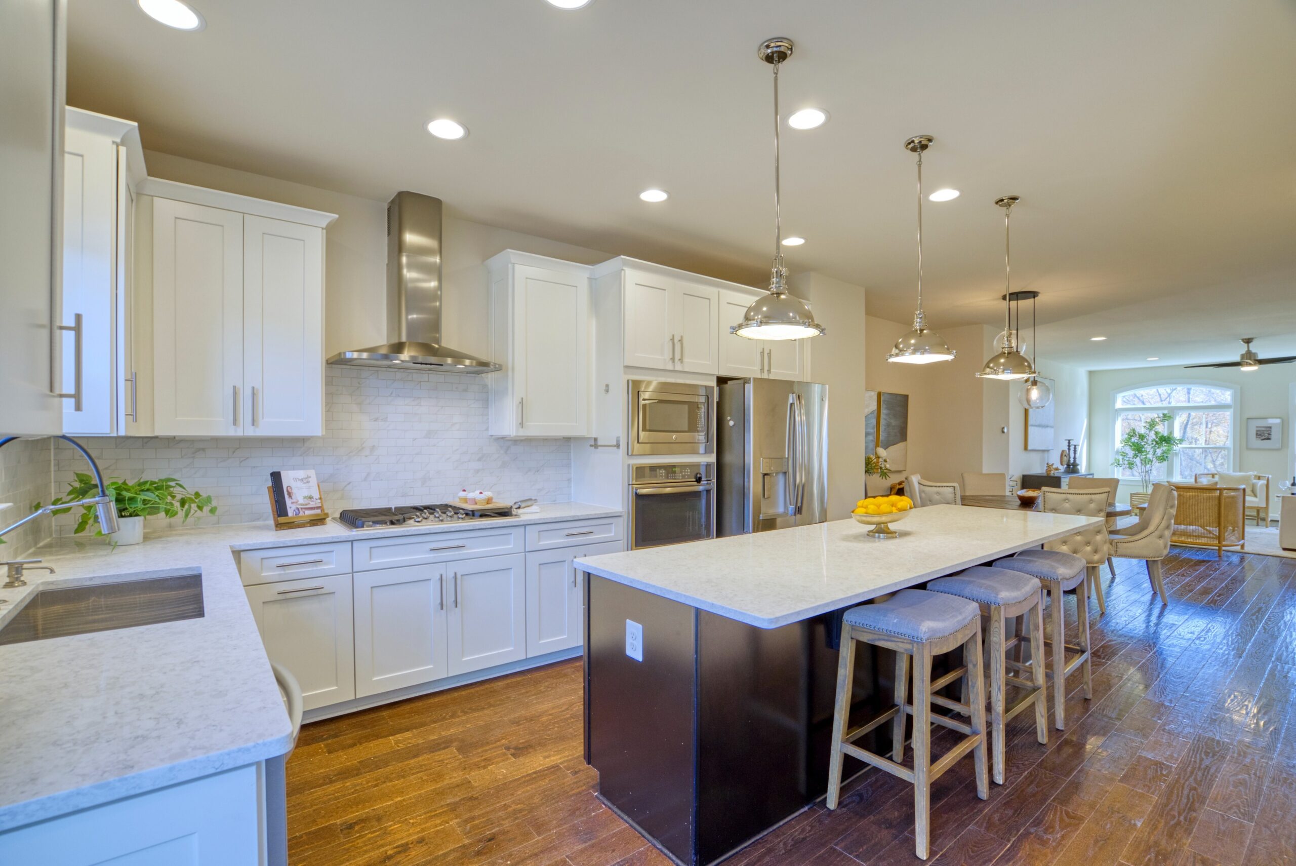 Professional interior photo of 3165 Virginia Bluebell Ct, Fairfax - showing the white kitchen and large island from an angle with view towards the living room