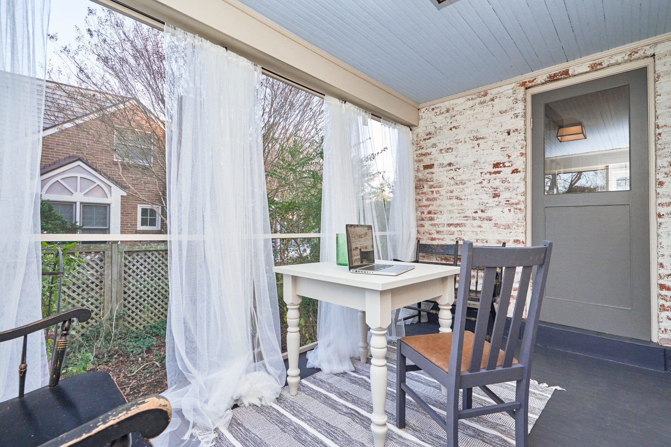 Professional interior photo of 5933 16th St N, Arlington, VA - showing the sunroom with a small desk and billowing gauzy white curtains