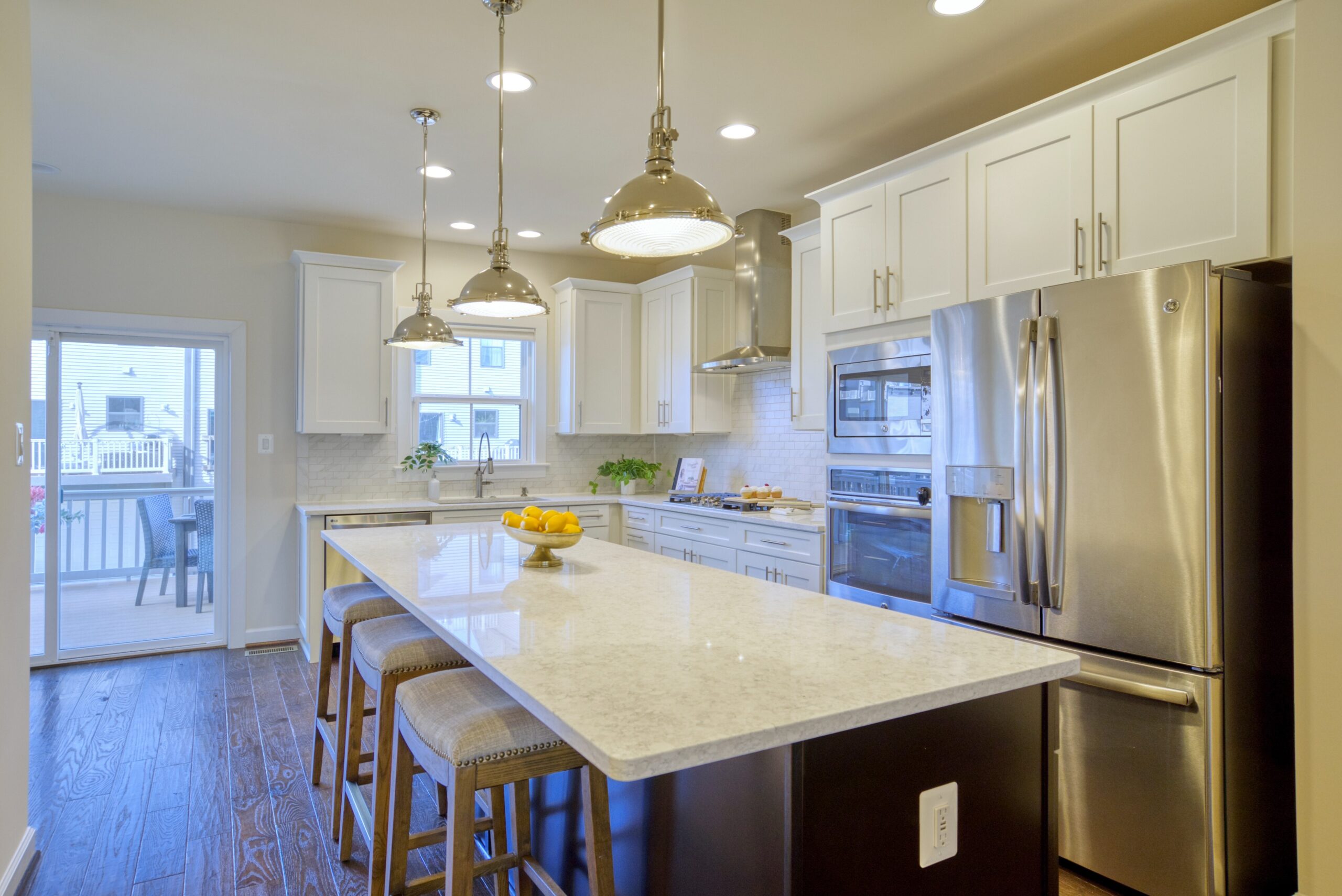 Professional interior photo of 3165 Virginia Bluebell Ct, Fairfax - showing the white kitchen and large island from an angle with view towards the rear deck