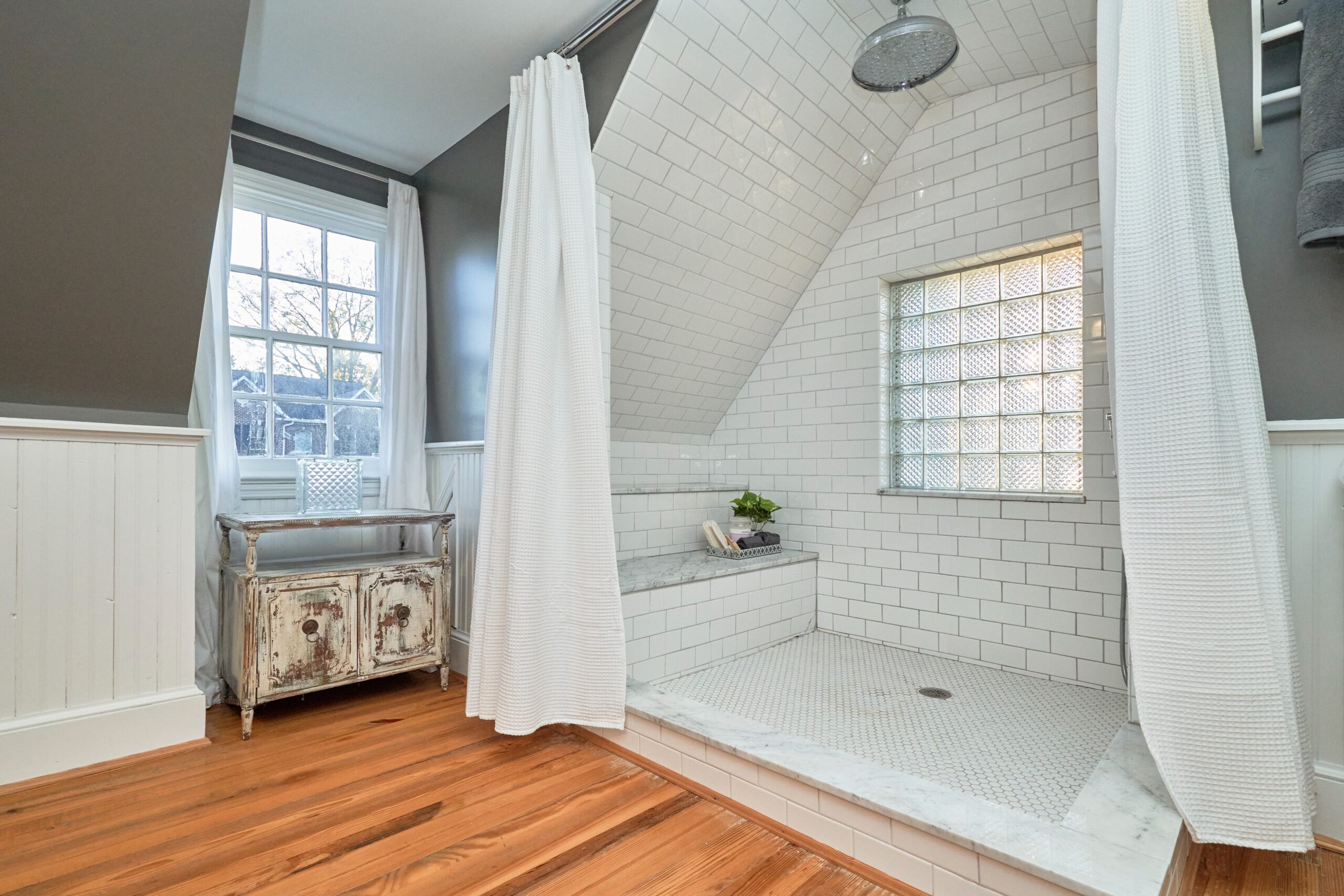 Professional interior photo of 5933 16th St N, Arlington, VA - showing the custom tiled large shower with rain head above and white subway tile from floor and all the way to cover the ceiling. zero entry shower, large white shower curtains surrount it.