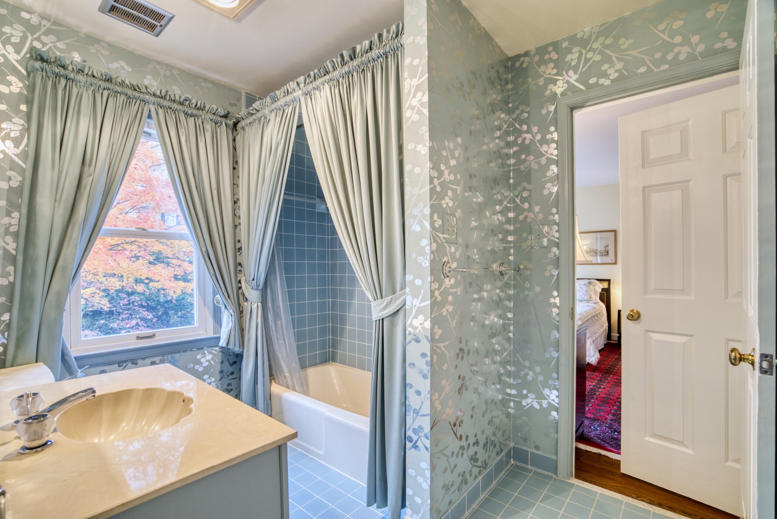 Interior professional photo of 1324 Skipwith Road - a full bathroom with antique blue shiny wallpaper and long window and shower curtains