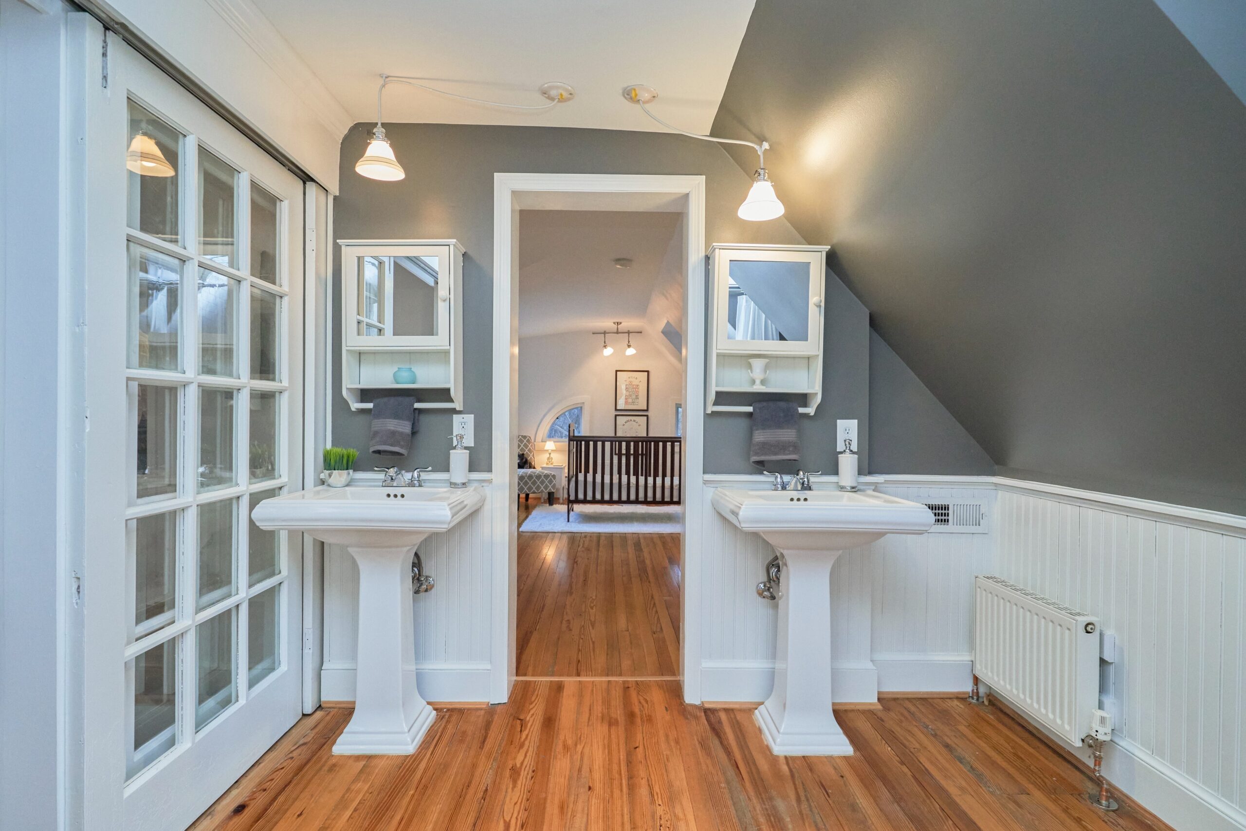 Professional interior photo of 5933 16th St N, Arlington, VA - showing the master bathroom with sinks on either side of a doorway which leads to a third bedroom