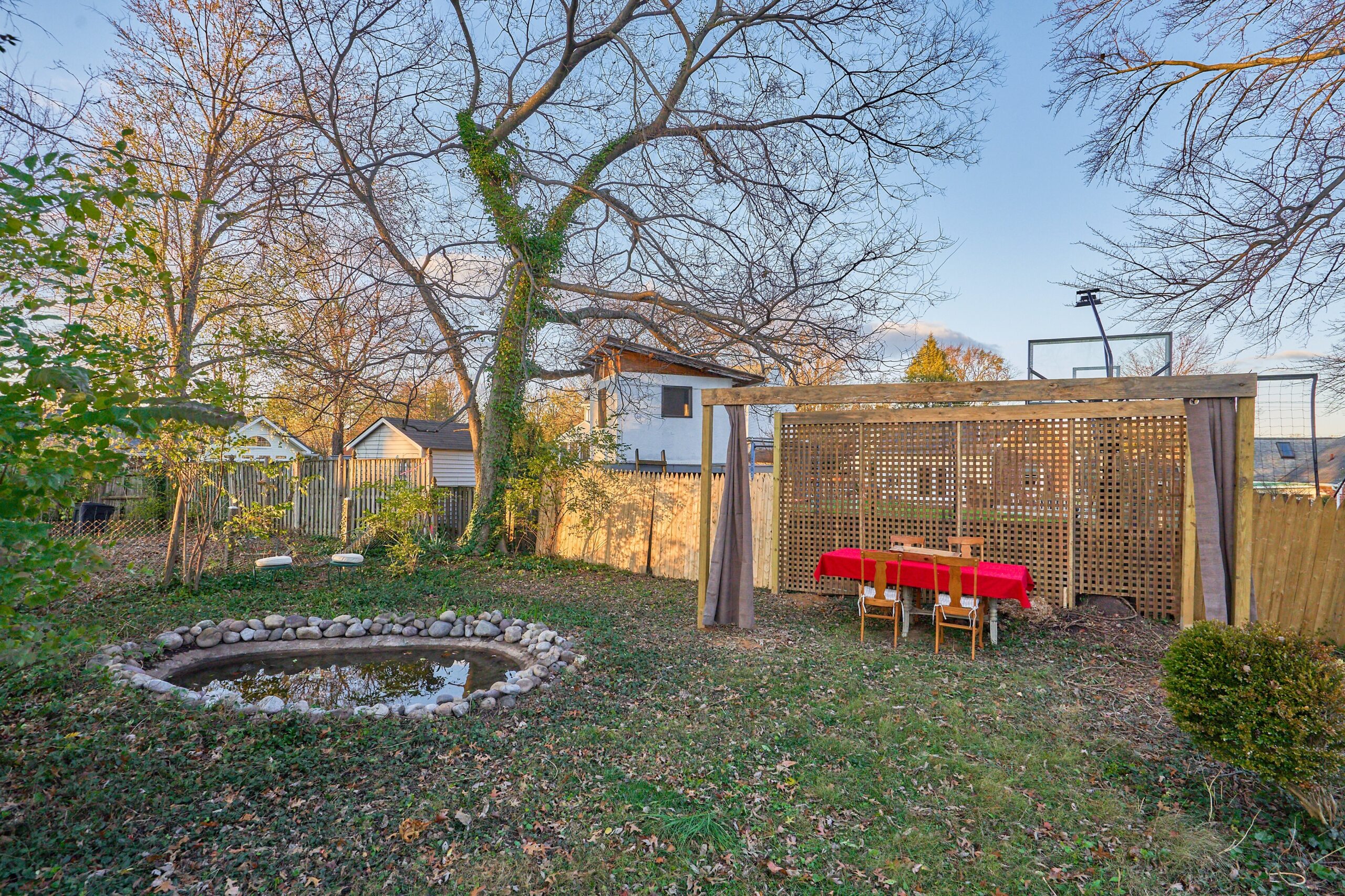 Professional exterior photo of 5933 16th St N, Arlington, VA - showing the back yard with a koi pond and an open-air shelter for a dining table with red tablecloth