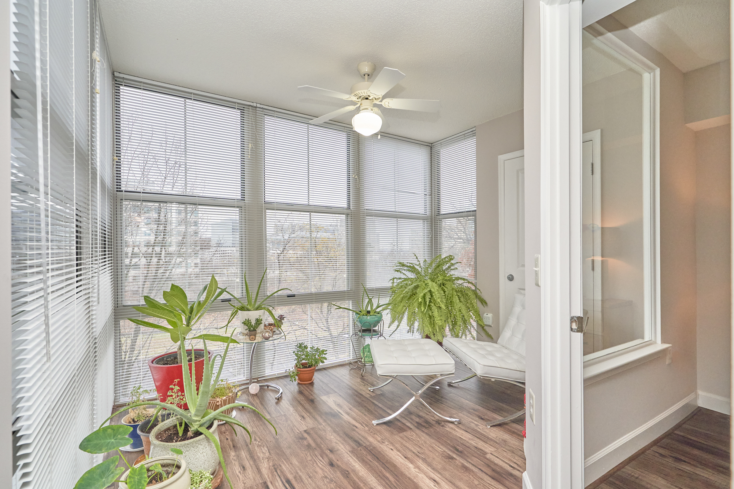 Interior professional photo of 11800 Sunset Hills Road Unit #811, showing the sunroom with several potted plants on the floor around the edge