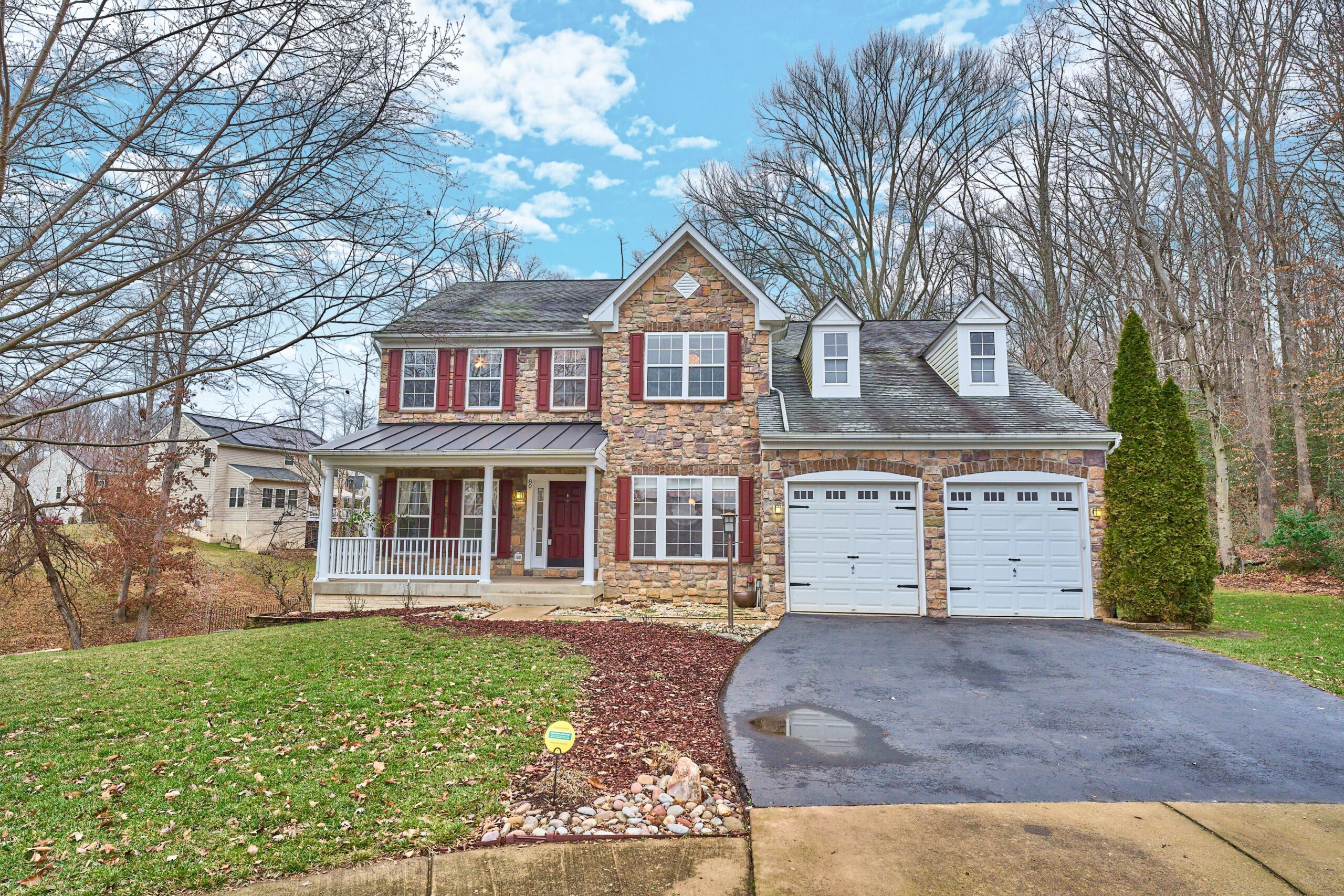 Professional exterior photo of 80 Brentsmill Drive in Stafford, Virginia - showing the front stone facade and 2 white garage doors
