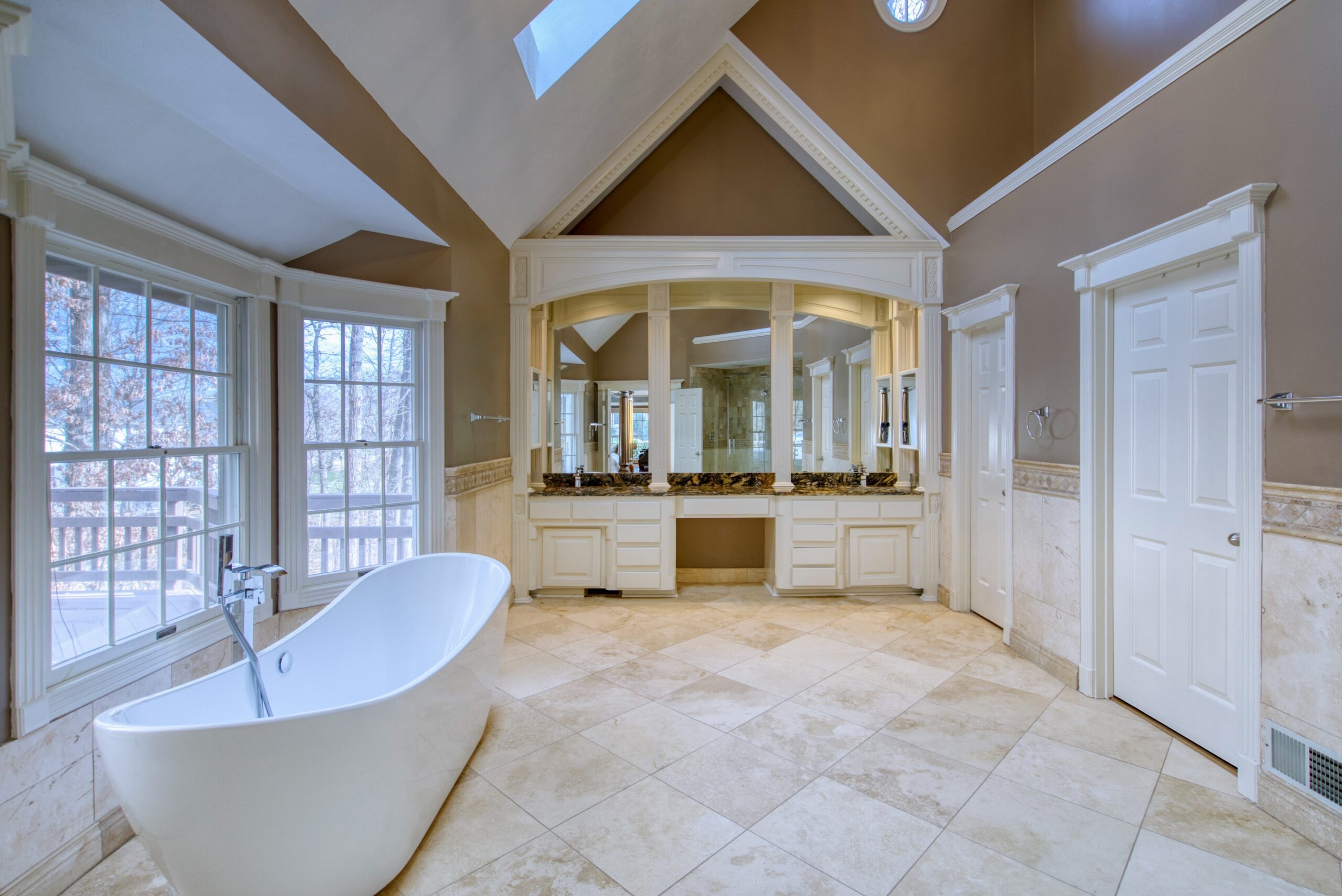Interior professional photo of 21024 Starflower Way in Ashburn, VA - showing the primary bathroom with vaulted ceiling, skylights, soaking tub, and imported tilework