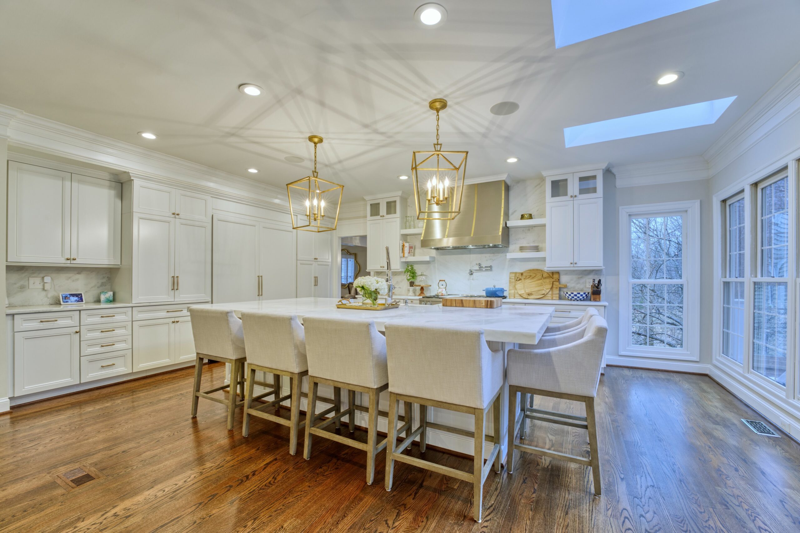 Professional interior photo of 47572 Compton Circle, Sterling, VA - showing the large open kitchen and island, skylights, white cabinets, and brushed gold accents