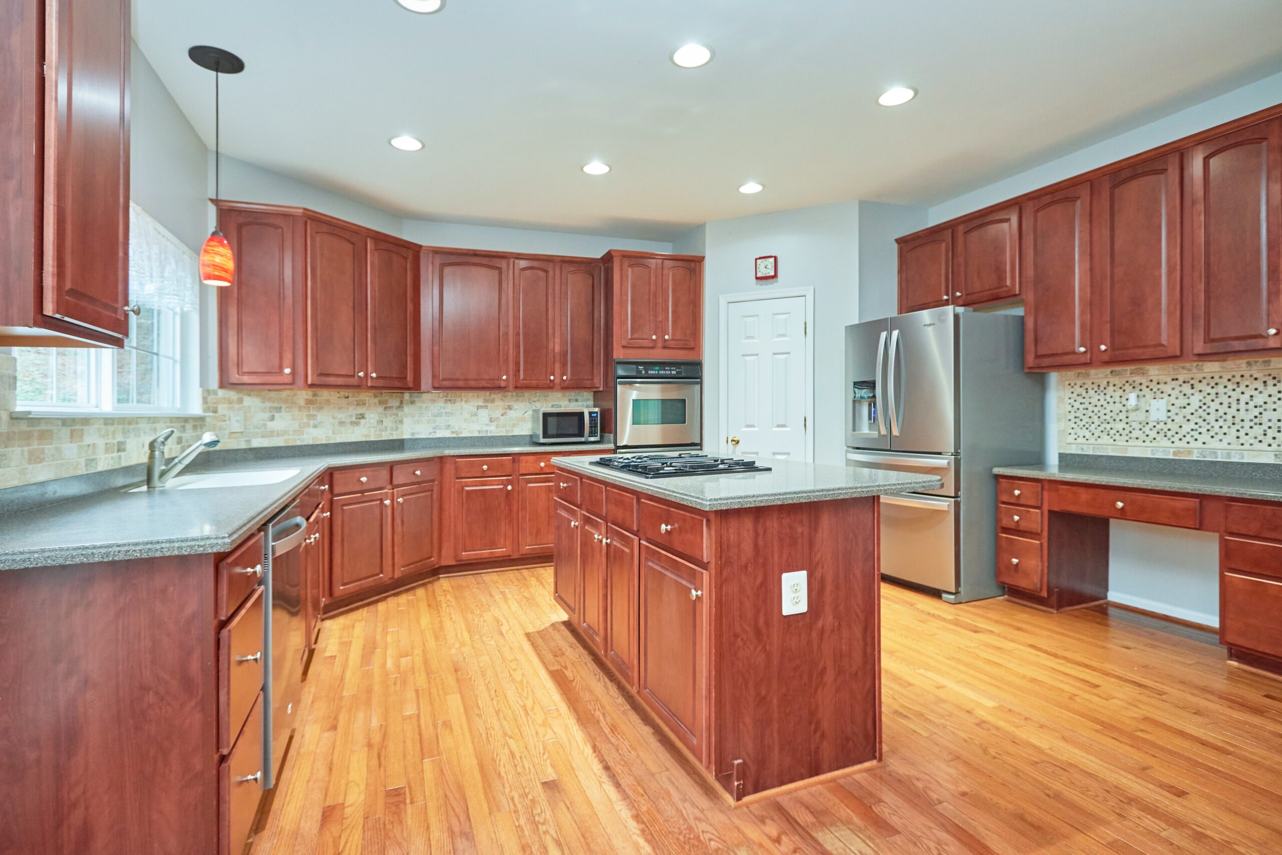 Professional interior photo of 80 Brentsmill Drive in Stafford, Virginia - showing the kitchen with hardwood floors, cherry style cabinets and granite counters