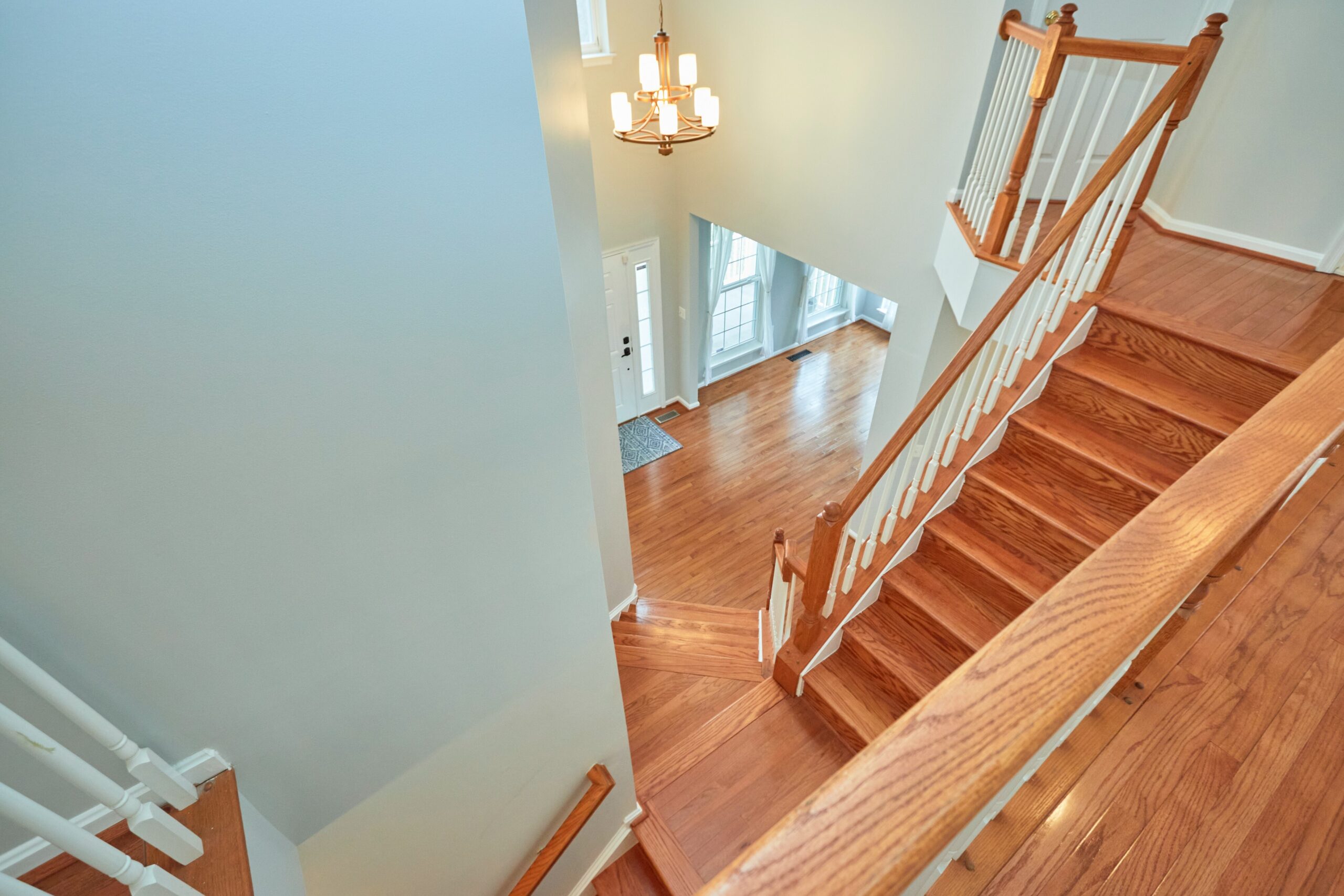 Professional interior photo of 80 Brentsmill Drive in Stafford, Virginia - showing the view from the top floor looking down the staircase toward the front call. All hardwood floors.