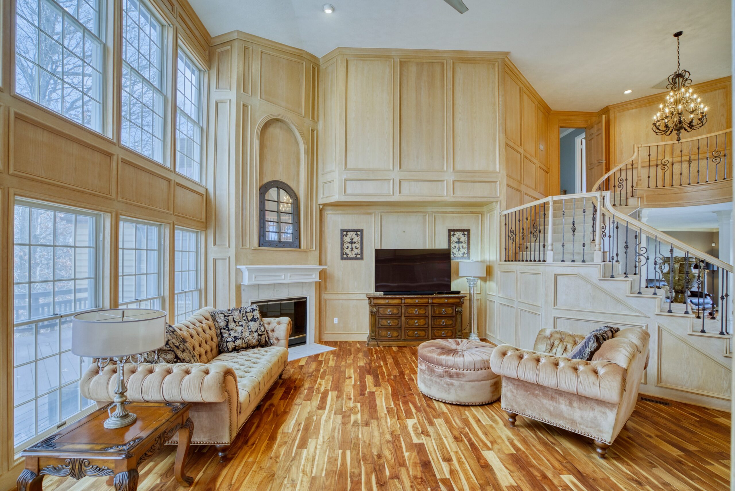 Interior professional photo of 21024 Starflower Way in Ashburn, VA - showing the 2-story grand living room with custom wood paneled walls