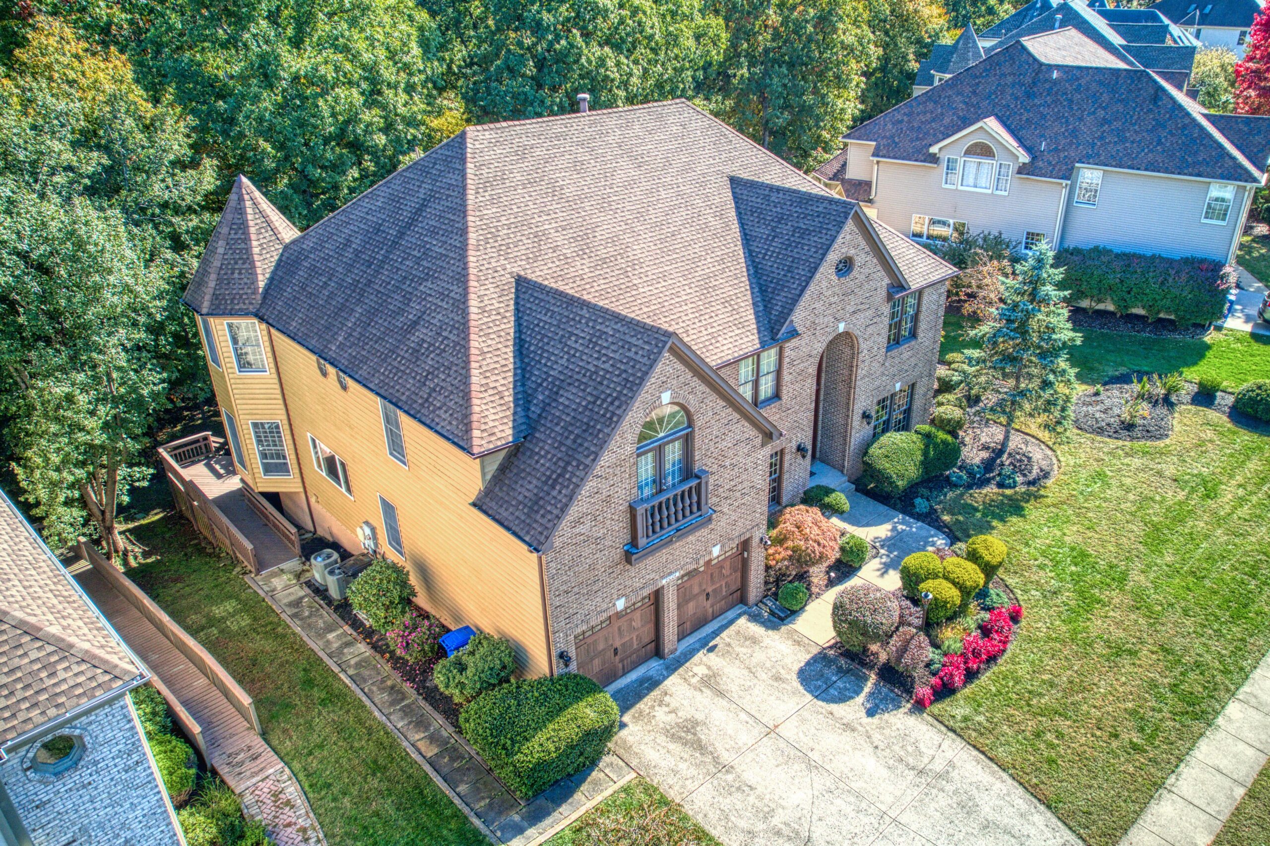 Aerial professional exterior photo of 21024 Starflower Way in Ashburn, VA - showing the entire brown brick home from the front at an angle