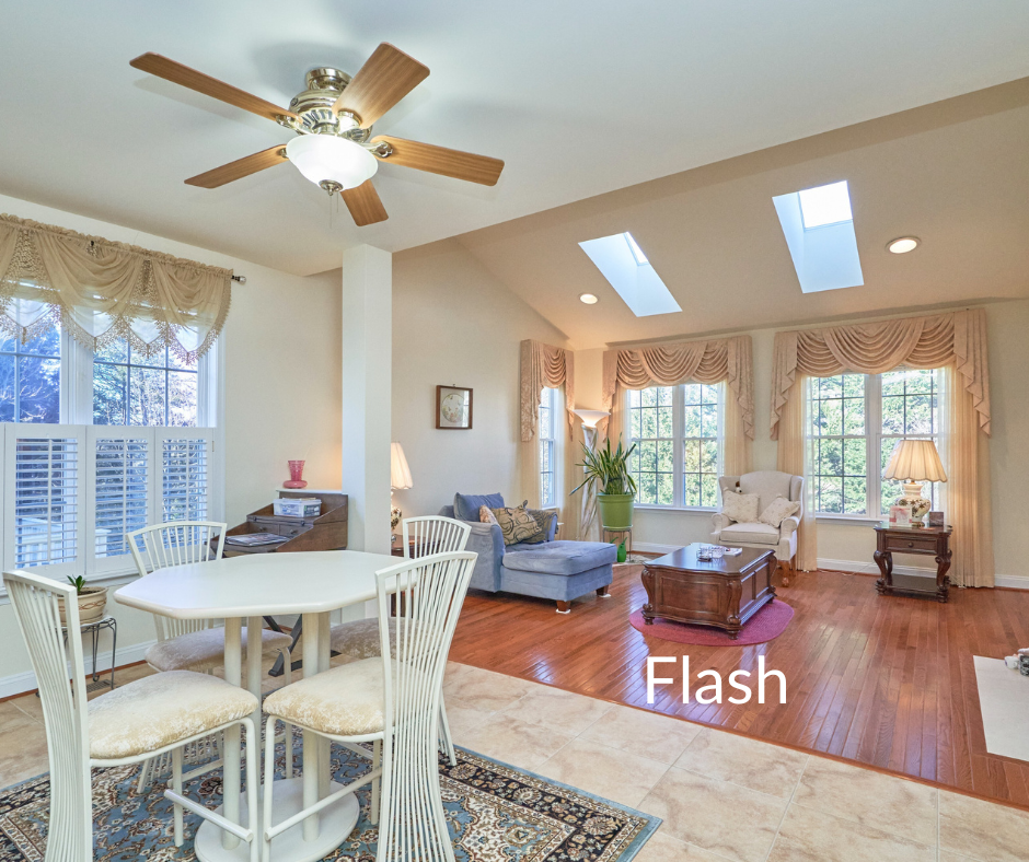 Professional Flash photo of a living/dining room with skylights, white walls and ceiling, and hardwood floors. Label "Flash" overlay in white