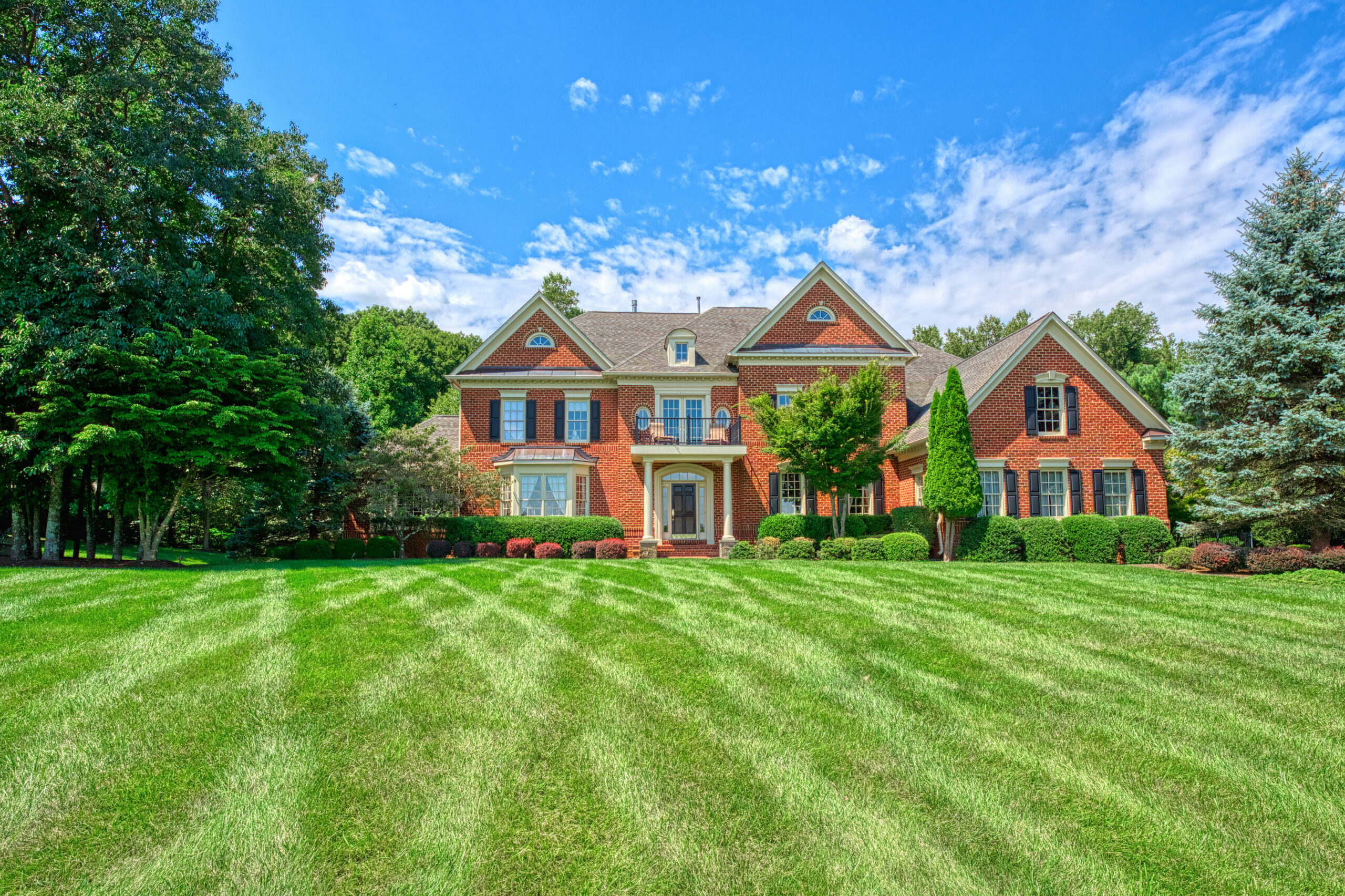 Professional exterior photo of 17087 Bold Venture Drive, Leesburg - showing the large lawn leading up to the red brick stately home