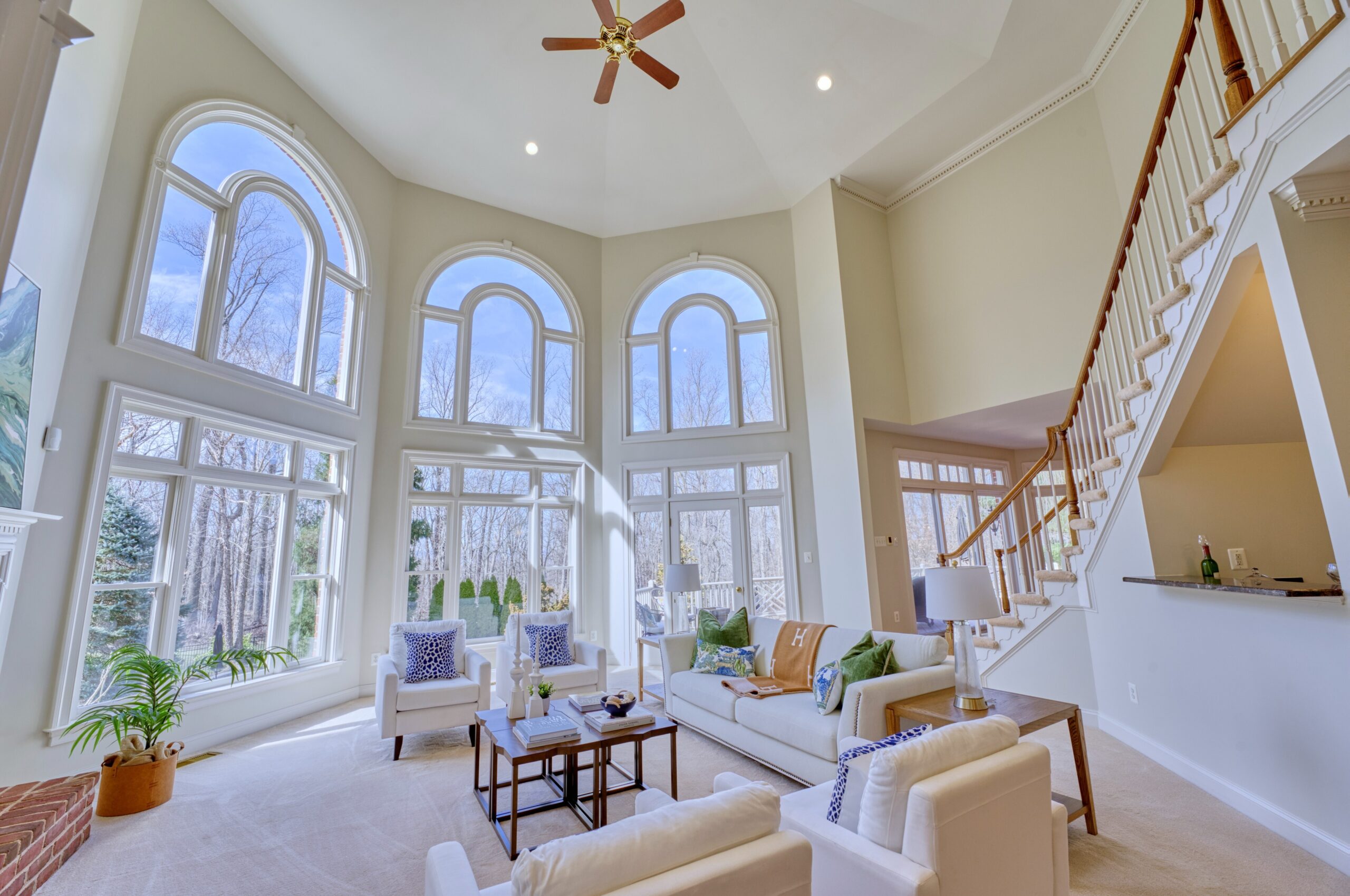 Professional interior photo of 17087 Bold Venture Drive, Leesburg - showing the large 2-story living room with ceiling fan and staircase to the second floor