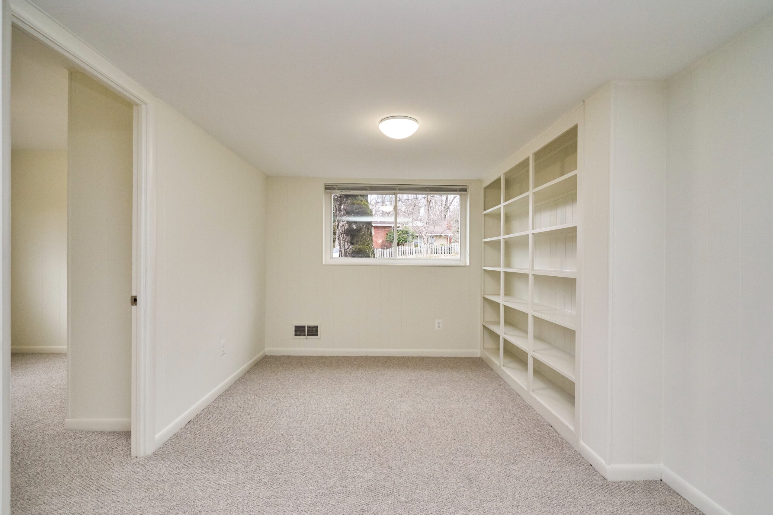 Professional interior photo of 3482 Mildred Drive in Falls Church virginia, showing a basement room with beige carpeting and built-in shelving along one wall