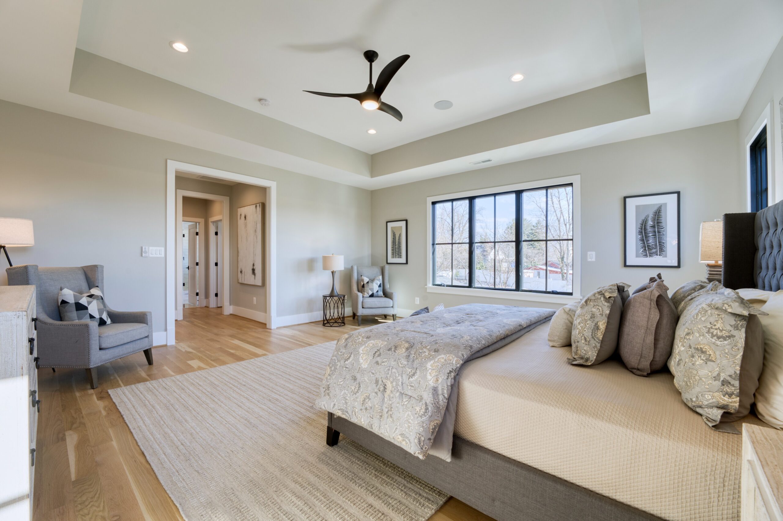 Professional interior photo of 1624 Dempsey St, McLean, VA - showing the primary bedroom with deep trey ceiling, hardwood floors and connection to adjoining bathroom