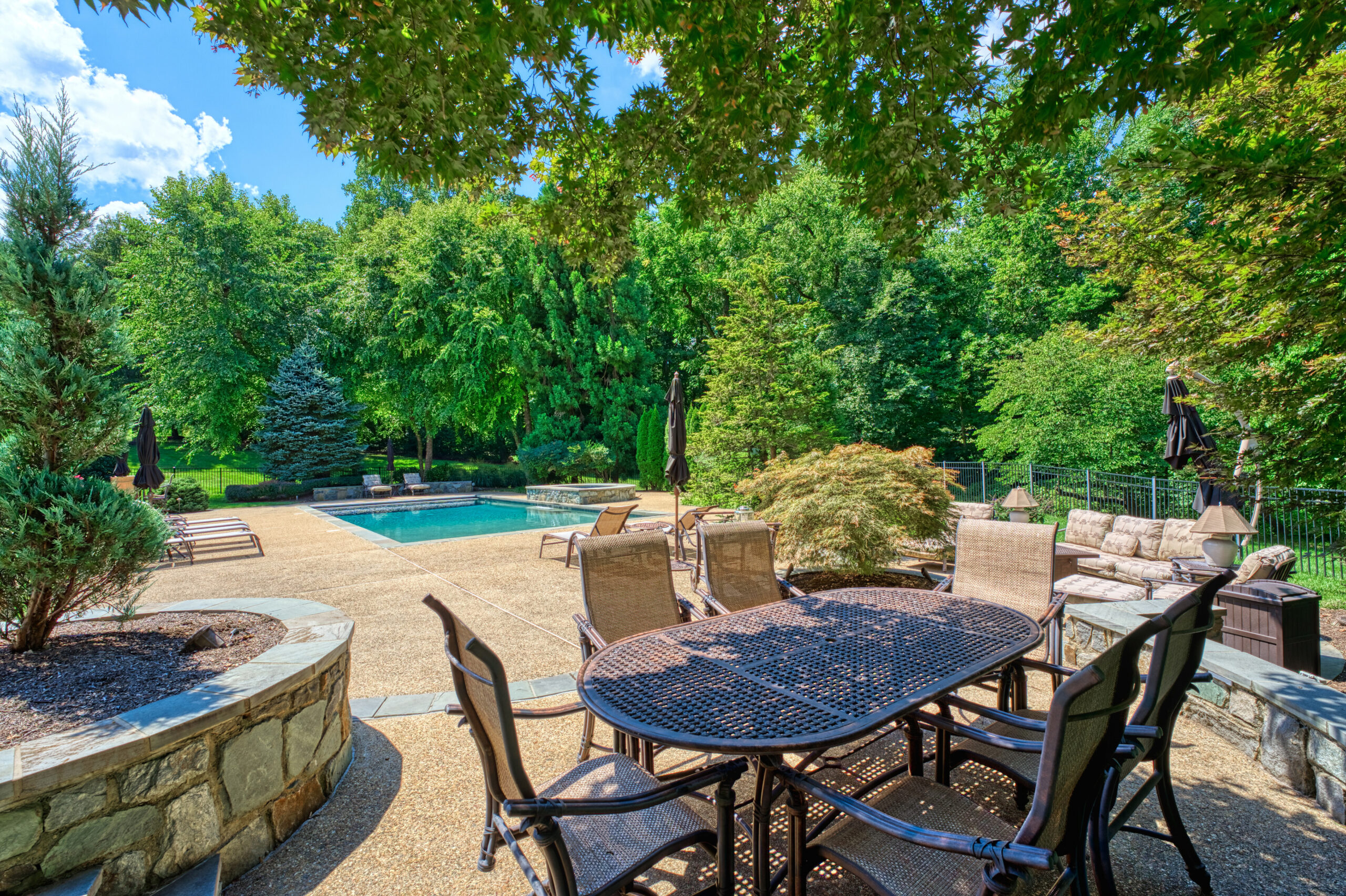 Professional exterior photo of 17087 Bold Venture Drive, Leesburg - showing the view from one of the shaded patio areas looking towards the pool