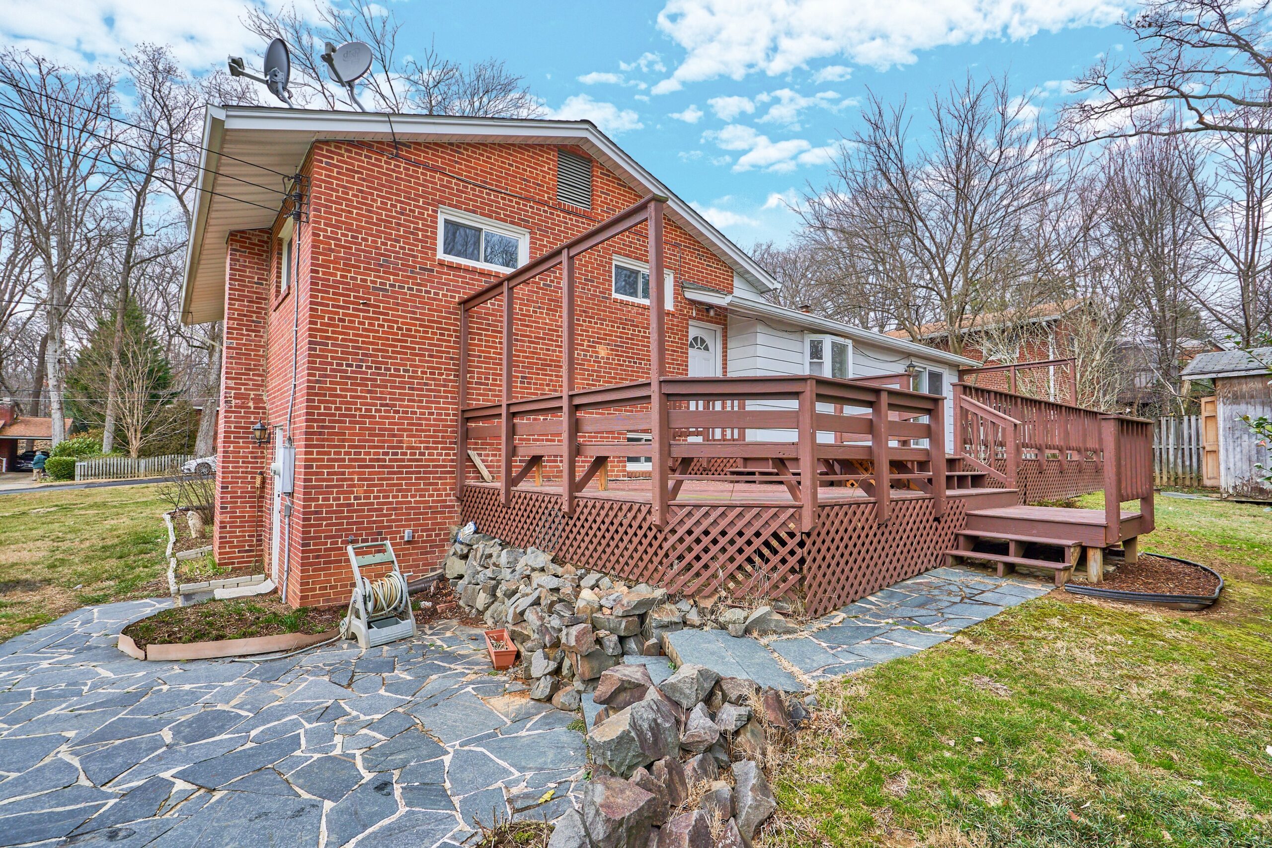 Professional exterior photo of 3482 Mildred Drive in Falls Church virginia, showing the side and back with large deck and cobblestone path, steps and patio