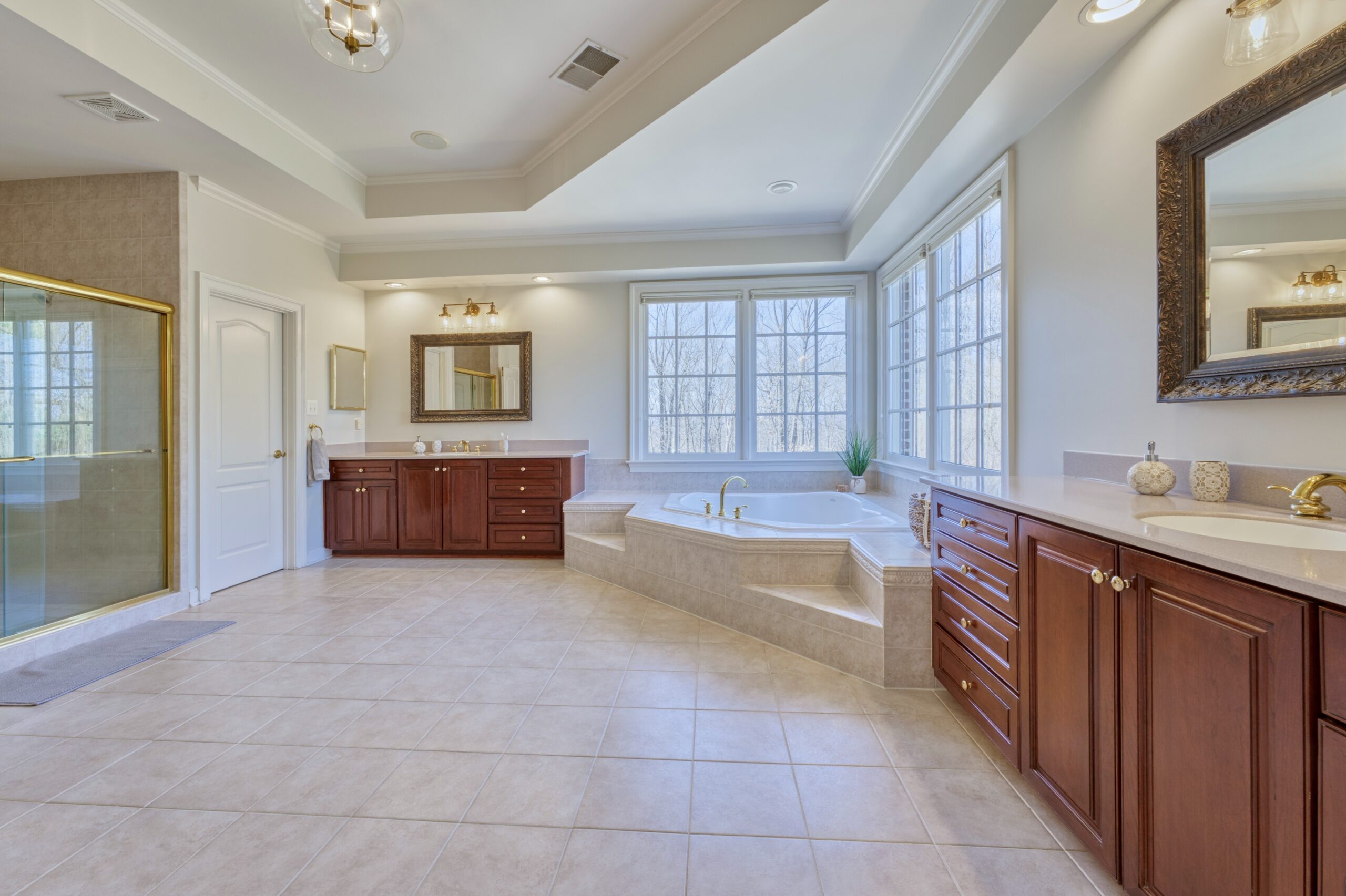 Professional interior photo of 17087 Bold Venture Drive, Leesburg - showing the primary bathroom with separate vanities, soaking tub in the corner windows and large shower